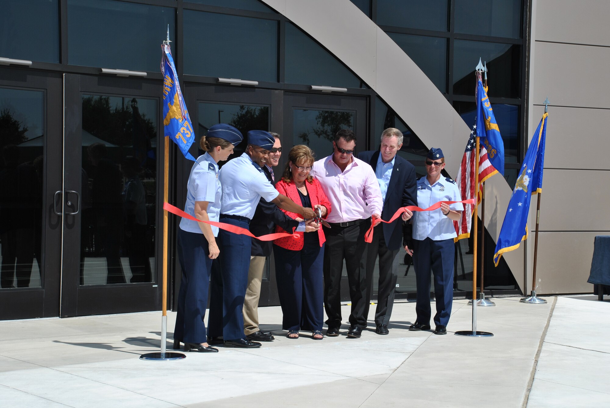 At center, Marsha Pfingston cuts the ribbon July 30, to the new Recruit/Family In-processing and Information Center at Joint Base San Antonio-Lackland, Texas, that was dedicated to her late husband, 10th Chief Master Sergeant of the Air Force Gary Pfingston. Assisting her, from left, were Col. Michele Edmondson, 737th Training Group commander; Col. Trent Edwards, 37th Training Wing commander; her sons, Mark and Brad Pfingston; retired 12th CMSAF Eric Benken; and Lt. Col. Jill Murphy, 737th Training Support Squadron commander. (U.S. Air Force Photo/Jennifer Schneider/released)