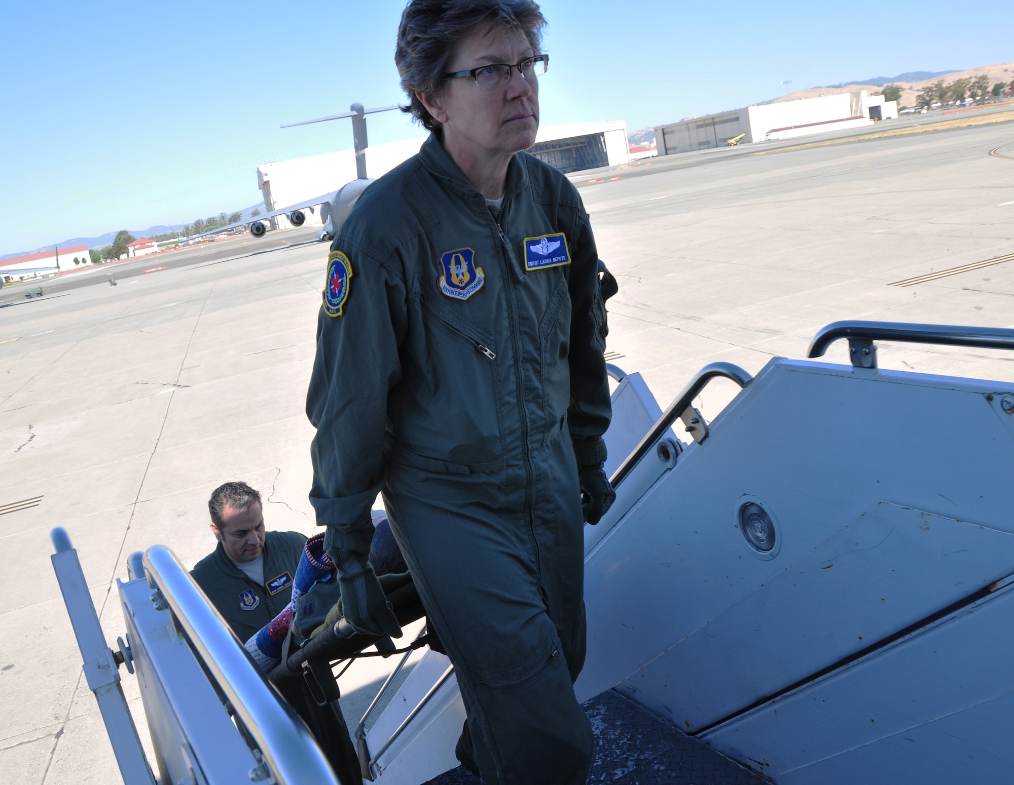 Chief Master Sgt. Laura Nepute, 349th Aeromedical Evacuation Squadron technician, and Master Sgt. Gabriel Aguilar, 349th AES technician, perform a simulated patient litter carry into a McConnell KC-135 Stratotanker at Travis Air Force Base, July 25, 2014, For the men and women of the of the 931st Air Refueling Group and 349th Aeromedical Evacuation Squadron the versatility of the KC-135 and lifesaving combat medical care go hand-in-hand. (U.S. Air Force photo by Staff Sgt. Abigail Klein)
