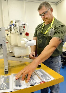 John Shrabel, a pneudraulics mechanic with the 76th Commodities Maintenance Group, checks parts for the VCS, the vapor cycle cooling system, the motor that regulates the air flow and cools the electronics on board the F-22 Raptor. (Air Force photos by Kelly White)