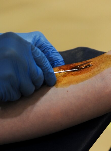 A Red Cross volunteer inserts a needle into the arm of U.S. Air Force Capt. Victoria Bobo, 23d Operations Support Squadron weather flight commander, during a blood drive at Moody Air Force Base, Ga., July 30, 2014.  Before inserting the needle, the vein is marked and cleaned with a combination of betadine and iodine. (U.S. Air Force photo by Airman 1st Class Alexis Millican/Released)