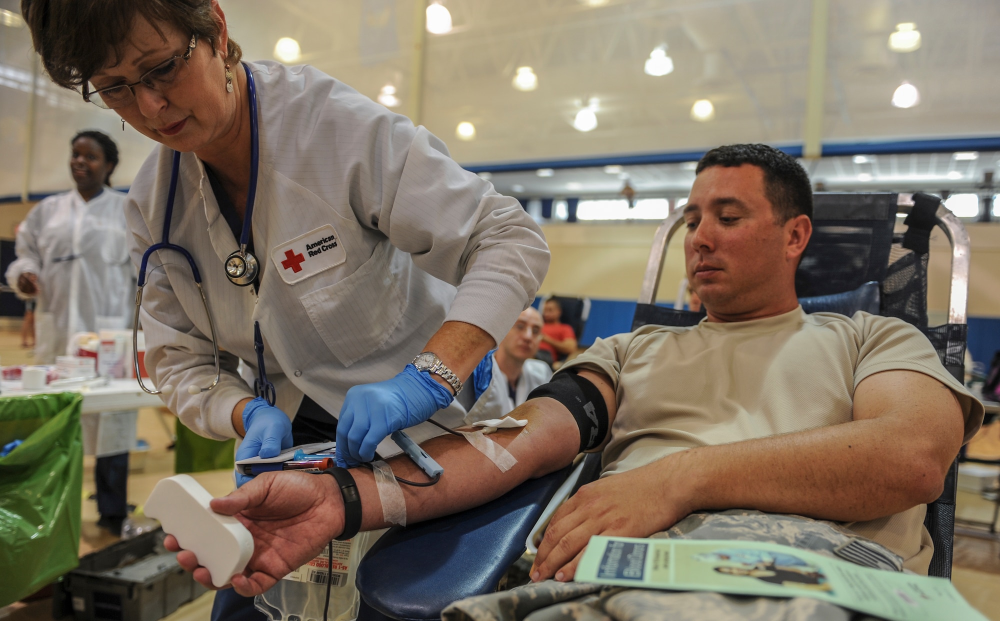 U.S. Air Force Tech. Sgt. Jeremy Cross, 23d Maintenance Group NCO in charge of maintenance analysis, watches as a Red Cross volunteer fills specimen tubes after donating blood at Moody Air Force Base, Ga., July 30, 2014. Cross donated a pint of blood which could save up to three lives. (U.S. Air Force photo by Airman 1st Class Alexis Millican/Released)