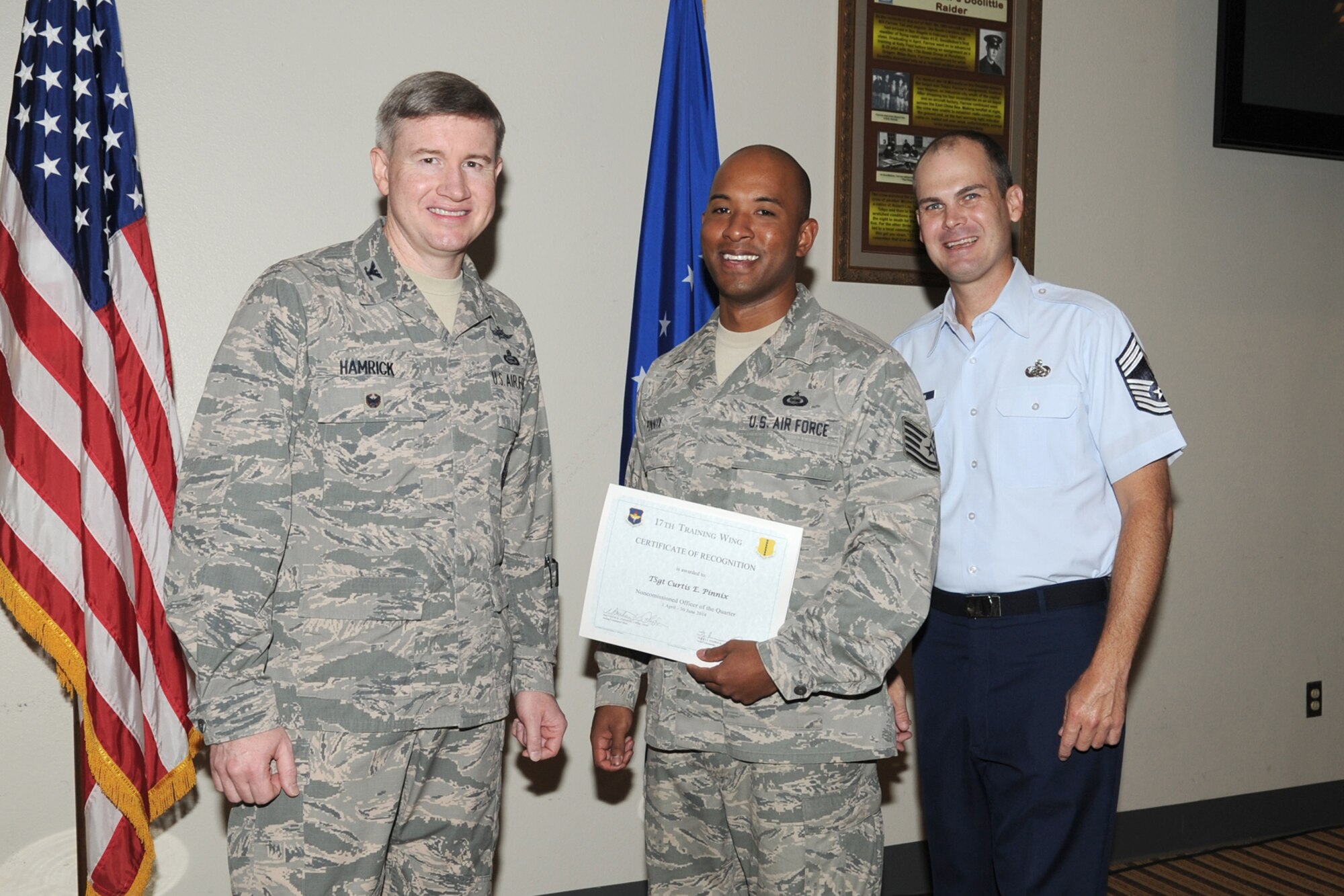 GOODFELLOW AIR FORCE BASE, Texas - Col. Terry J. Hamrick Jr., 17th Training Wing Vice Commander, and Chief Master Sgt. Matthew K. Johnson, 17th Mission Support Group superintendent, present the 17th Training Wing NCO of the Quarter award to Tech. Sgt. Curtis E. Pinnix, 315th Training Squadron, during the wing quarterly awards ceremony at the Event Center here July 21. (U.S. Air Force photo/ Staff Sgt. Laura R. McFarlane)