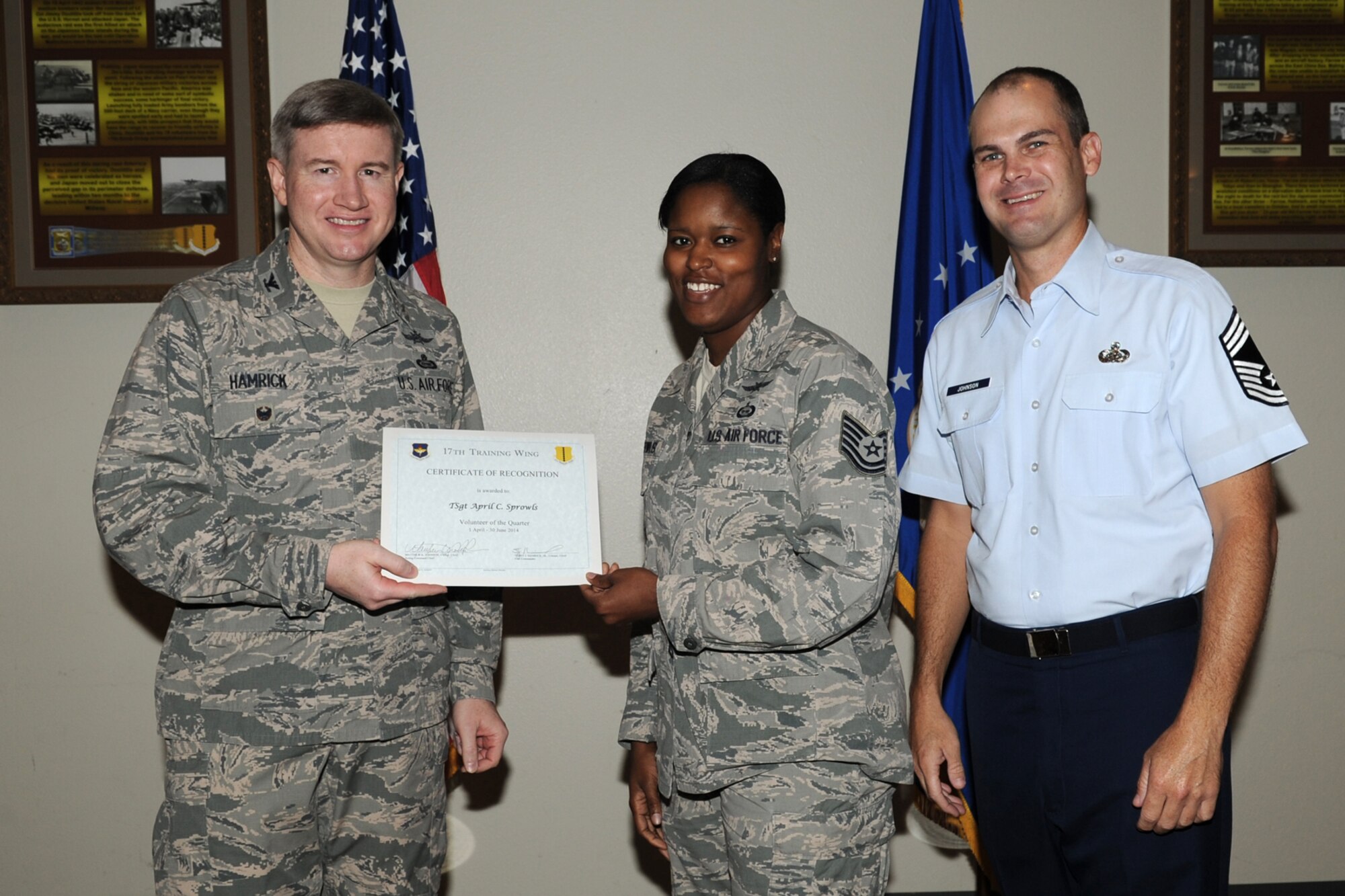 GOODFELLOW AIR FORCE BASE, Texas - Col. Terry J. Hamrick Jr., 17th Training Wing Vice Commander, and Chief Master Sgt. Matthew K. Johnson, 17th Mission Support Group superintendent, present the 17th Training Wing Volunteer of the Quarter Award to Tech. Sgt. April C. Sprowls, 315th Training Squadron, during the wing quarterly awards ceremony at the Event Center here July 21. (U.S. Air Force photo/ Staff Sgt. Laura R. McFarlane)