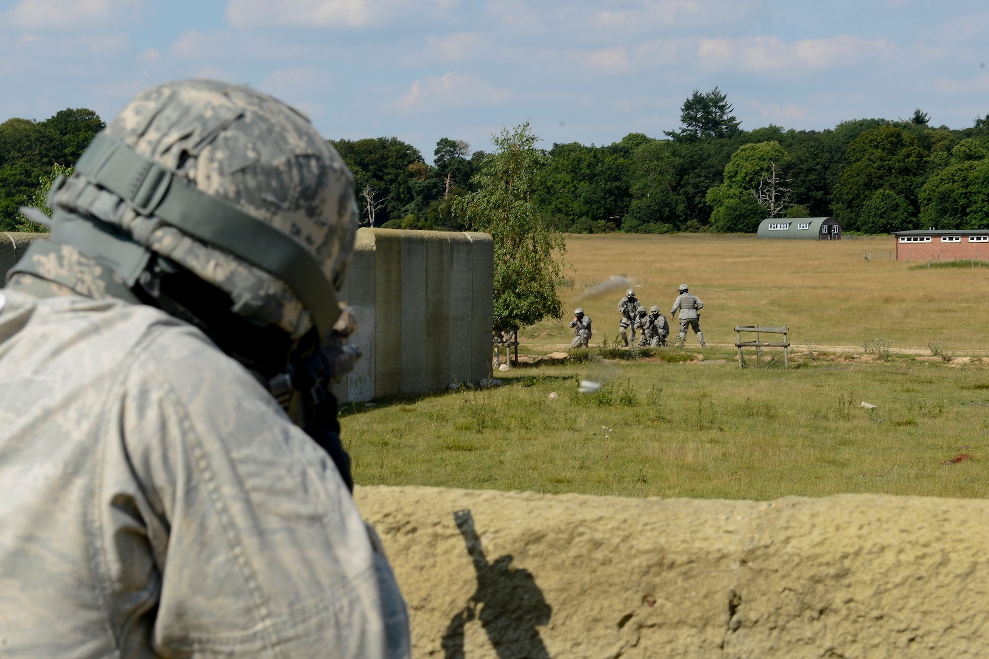 A simulated opposing force member (left), fires at 48th Security Force Squadron Airmen in a high-valued target scenario during force-on-force training at the Stanford Training Area in Norfolk, England, July 29, 2014. (U.S. Air Force photo by Airman 1st Class Trevor T. McBride)