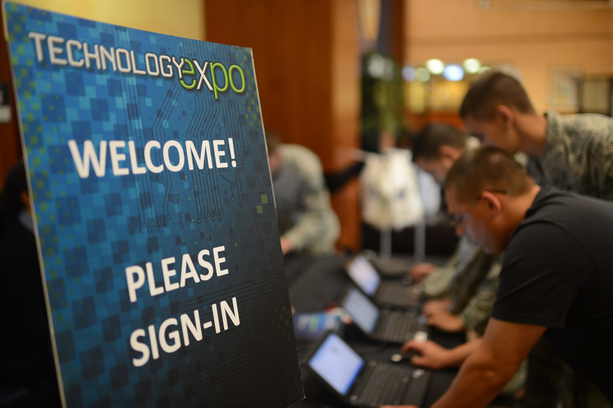 Airmen and families from the Spangdahlem community sign in to the 2014 Spangdahlem Technology Expo at Club Eifel, July 30, 2014. An estimated 250 attendees visited the expo throughout the four-hour event to talk, collaborate and request future technology products that could improve workcenters and operations. (U.S. Air Force photo by Senior Airman Gustavo Castillo/Released) 