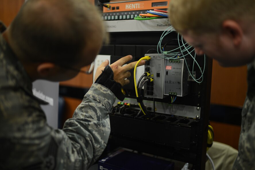 U.S. Air Force Staff Sgt. Jason Hart, left, a 606th Air Control Squadron cyber transport technician from Greenville, S.C.; and U.S. Air Force Staff Sgt. Donovan Nay, a 606th ACS cyber transport technician from Clemington, N.J., inspect a visual display of Anixter products at the 2014 Spangdahlem Technology Expo at Club Eifel July 30, 2014. This display showcased the different types of connectors and security products produced by the company. (U.S. Air Force photo by Senior Airman Gustavo Castillo/Released) 