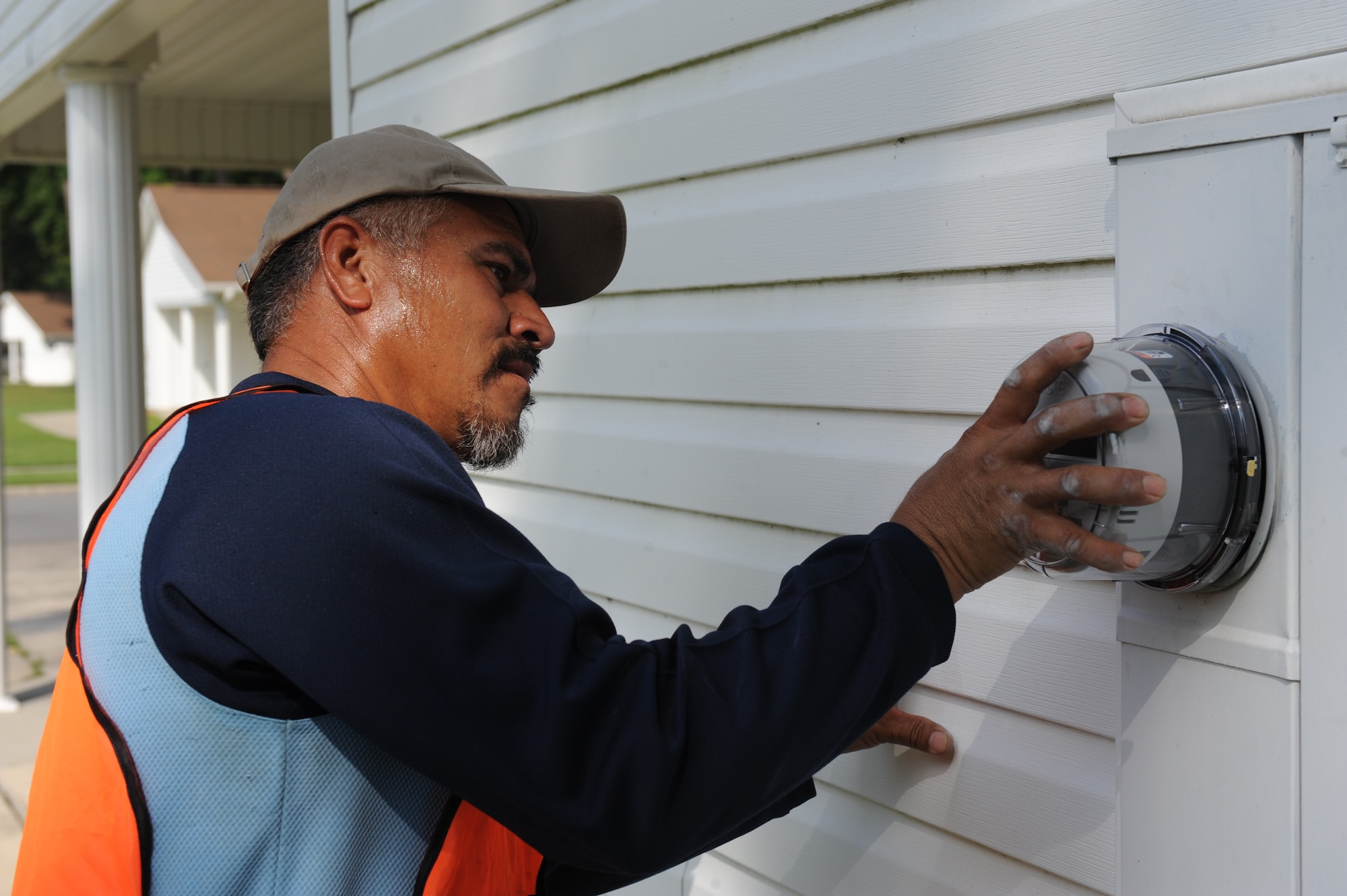 Lazaro Sierra, Sierra Enterprises owner, installs an electric meter to an on-base house July 23, 2014, at Seymour Johnson Air Force Base, North Carolina. Sierra and other workers installed meters on more than 600 on-base houses. (U.S. Air Force photo/Airman 1st Class Aaron J. Jenne)