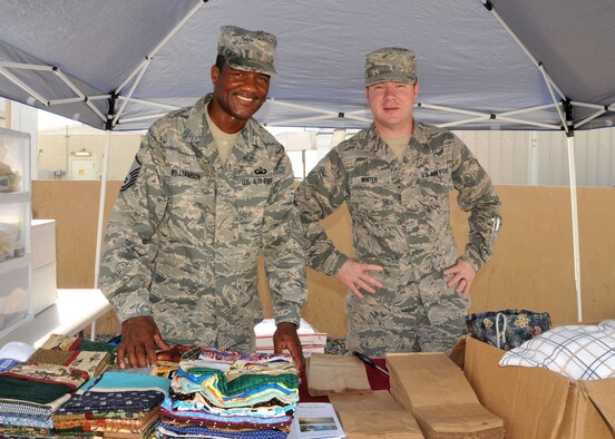 380th Air Expeditionary Wing chapel staff members Master Sgt. Andre Williamson and Senior Airman Erik Winter set up a tent to distribute donated items sent from home to Airmen and Soldiers assigned to the wing at an undisclosed location in Southwest Asia July 18, 2014. (U.S. Air Force photo by Senior Master Sgt. Eric Peterson/Released)