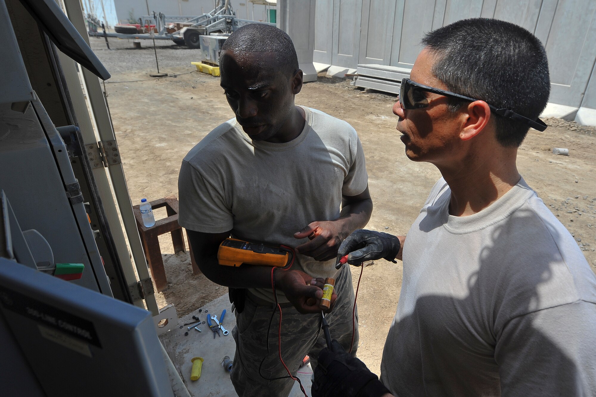 Brig. Gen. John T. Quintas (right), 380th Air Expeditionary Wing commander, and Senior Airman James Jenkins, a 380th Expeditionary Civil Engineer Squadron heating, ventilation, air conditioning and refrigeration journeyman, check the voltage of a fuse that runs a water pump July 28, 2014, at an undisclosed location in Southwest Asia. The group had just completed the installation of a water pump. Quintas spent the day with the chiller team to gain a better understanding of how Airmen contribute to the mission. (U.S. Air Force photo by Tech. Sgt. Russ Scalf/Released)