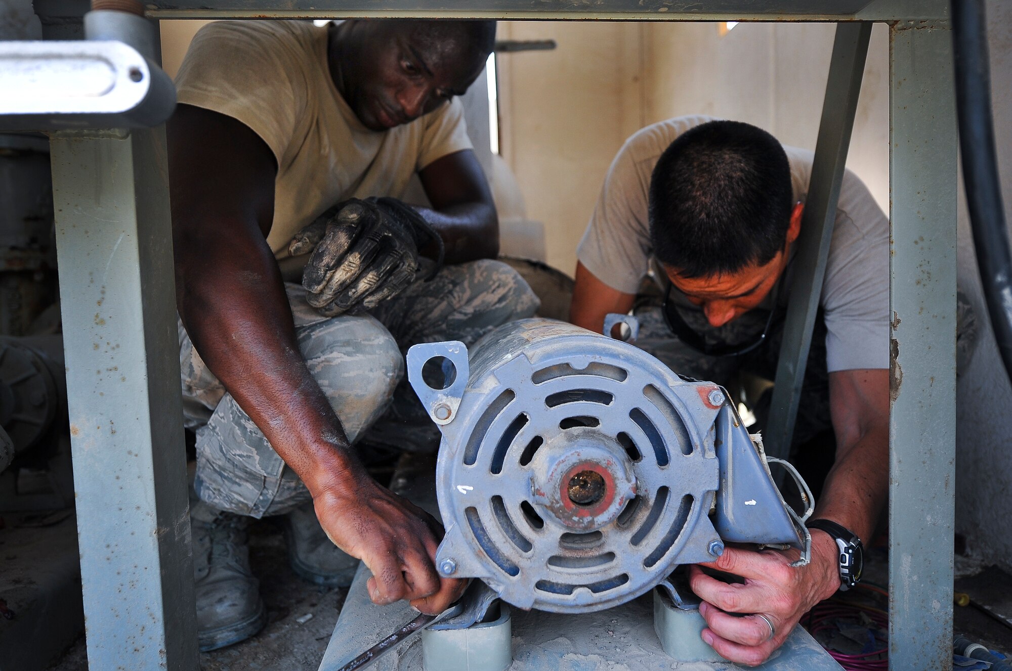 Brig. Gen. John T. Quintas (right), 380th Air Expeditionary Wing commander, and Senior Airman James Jenkins, a 380th Expeditionary Civil Engineer heating, ventilation, air conditioning and refrigeration journeyman, complete the installation of a water pump July 28, 2014, at an undisclosed location in Southwest Asia. Quintas spent the day assisting a chiller crew with maintenance to gain a better understanding of how Airmen contribute to the mission. (U.S. Air Force photo by Tech. Sgt. Russ Scalf/Released)