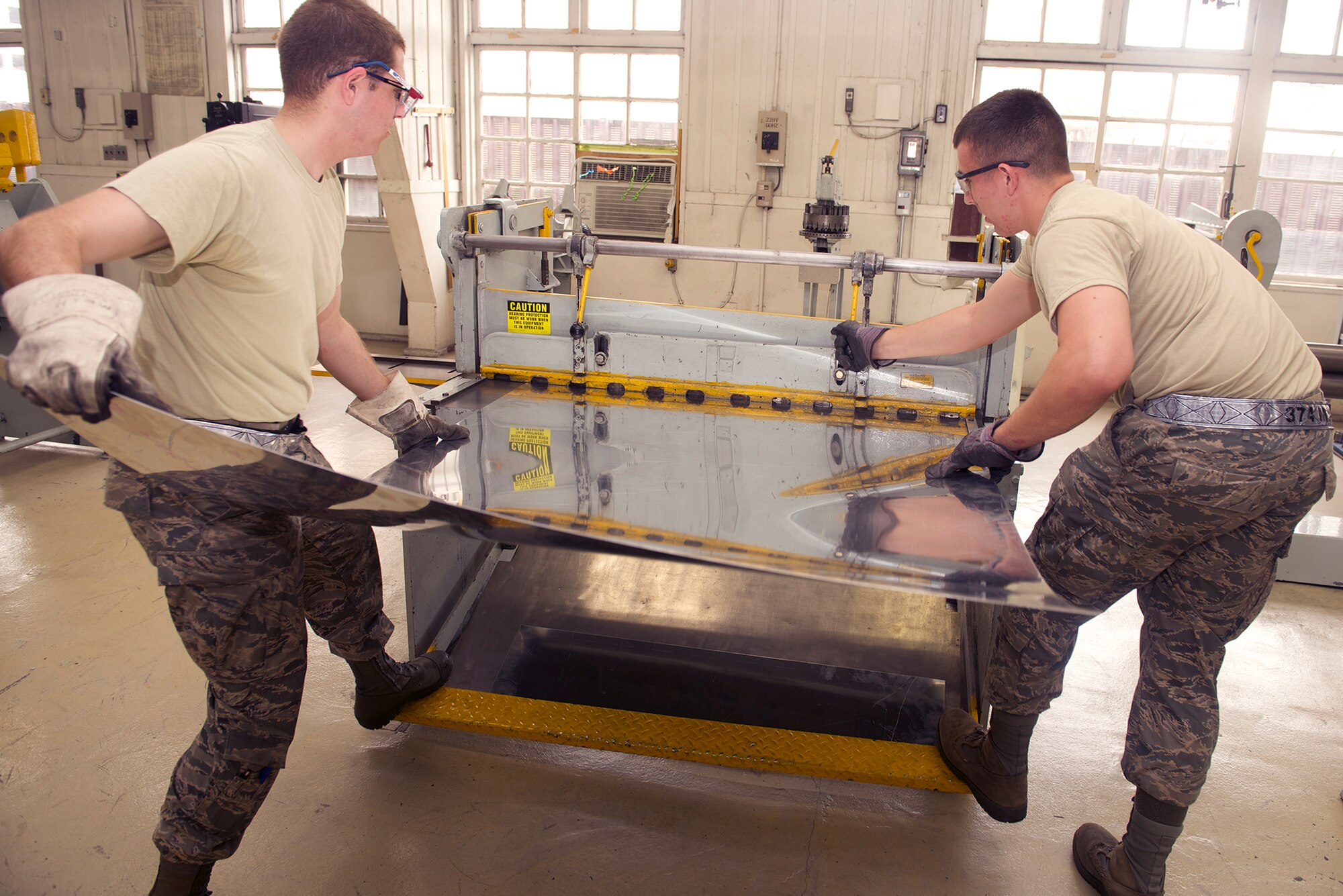 Airman 1st Class Cristian Landry and Senior Airman Derek Ham, 374th Maintenance Squadron aircraft structural maintainers, cut sheet metal using a foot-shear at Yokota Air Base, Japan, July 24, 2014.  Structural maintainers regularly practice their techniques in order to ensure high quality care for Yokota's C-130 Hercules fleet. (U.S. Air Force photo by Airman 1st Class David C. Danford)