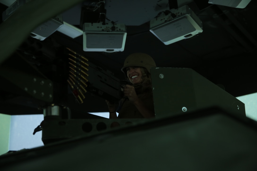 Keeter Moss, family readiness officer, Combat Logistics Battalion 7, opens fire on simulated enemies displayed in the Combat Convoy Simulator during the Rosie the Riveter vs. The Simulator event hosted at Camp Wilson, May 15, 2014. The spouses were split into fire teams and assigned to a vehicle for the duration of the simulation which included realistic environments in the Middle East, firefights, and crowd reactions to the use of weapons.
