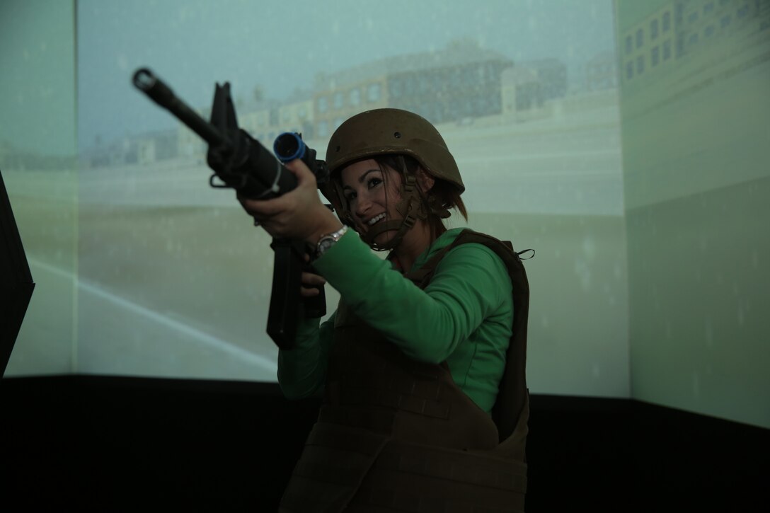 Sarah Sargent, wife of Lance Cpl. Clayton Sargent, provides suppressive fire to simulated targets on a screen of the Combat Convoy Simulator during the Rosie the Riveter Vs. The Simulator event hosted at Camp Wilson, May 15, 2014. The participants used modified M-16 A4 rifles which simulate the recoil and feel of an actual rifle.