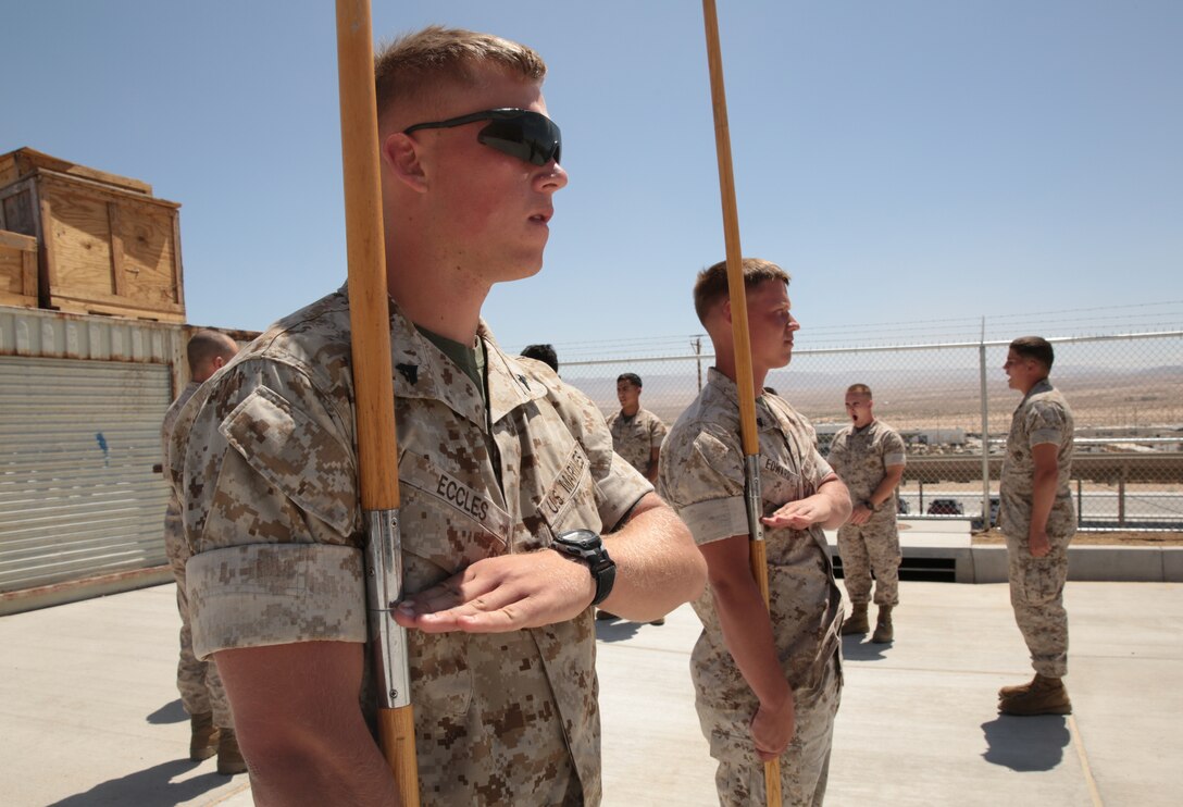 Cpl. Ryan Eccles, drafter and surveyor, Marine Wing Air Support Squadron 374, and Cpl. Steven M. Edwards, Marine Wing Air Support Squadron 374, execute a guidon salute during a guidon manual class at the 1st Tank Battalion classroom lot, May 20, 2014. Corporal's Course challenges Non-Commisioned Officers to learn Marine Corps history, leadership, fitness and drill.