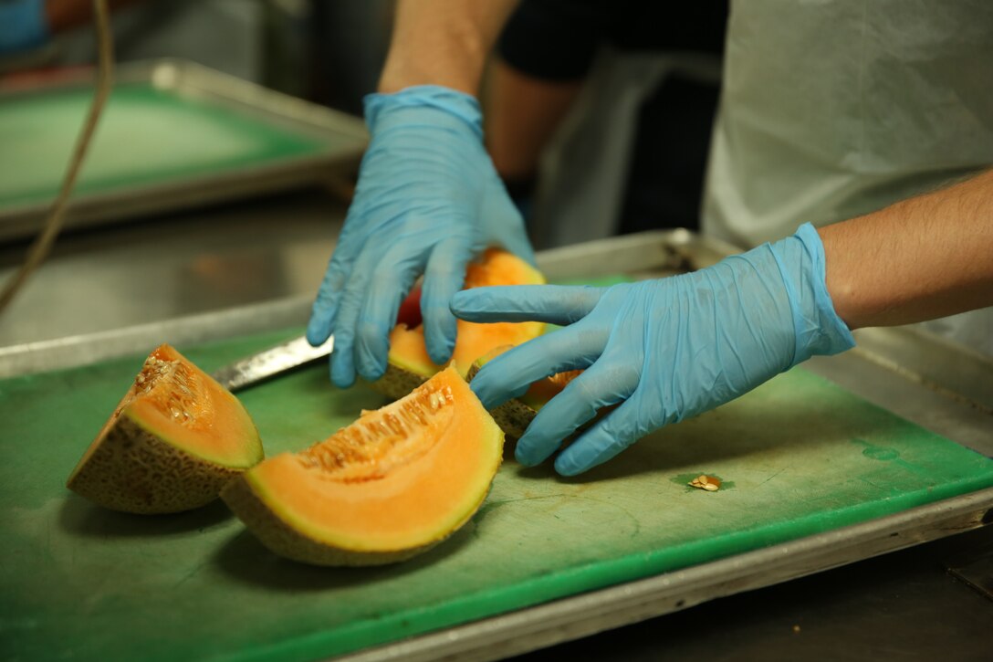 Cpl. Matt Cottrell, training non-commissioned officer, 3rd Battalion, 4th Marines, 7th Marine Regiment, chops cantaloupe during a volunteer event at the St. Vincent de Paul Village, May 25, 2014 The efforts of Marines and sailors helped feed approximately 500 citizens.