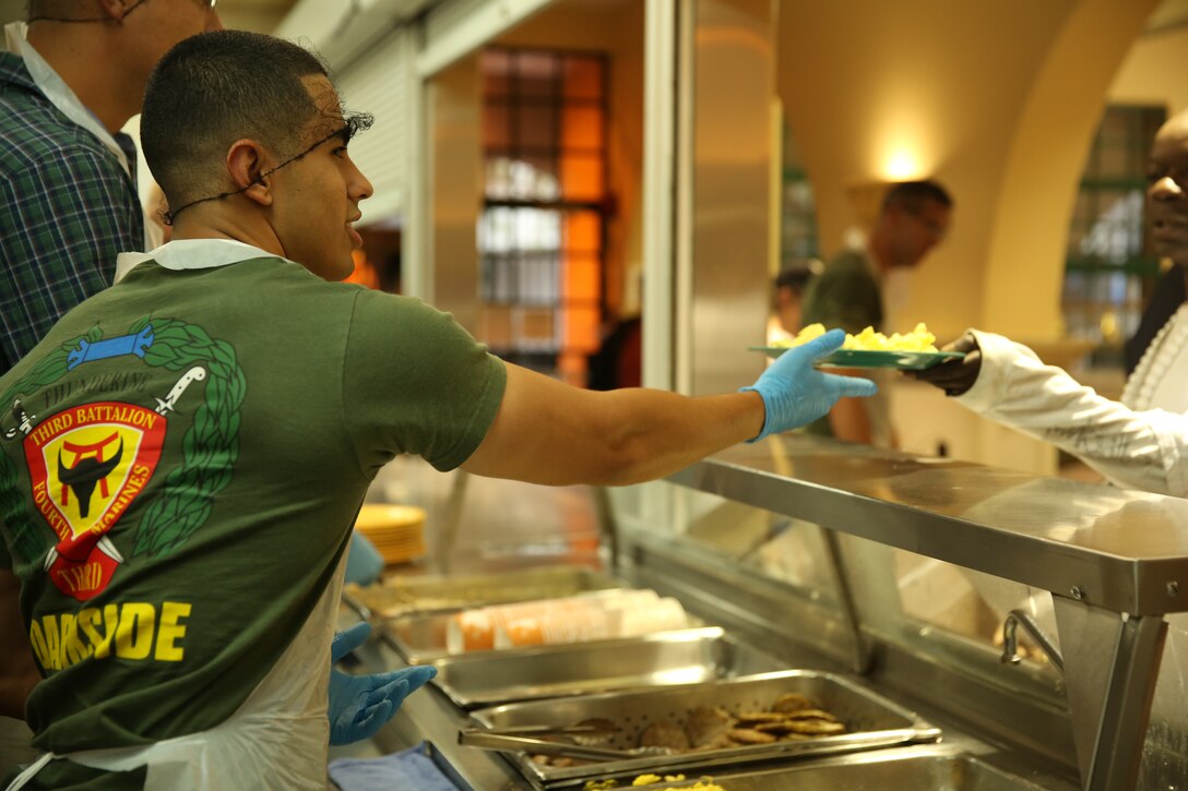 Cpl. Christian Martinez, chaplain assistant, 3rd Battalion, 4th Marines, 7th Marine Regiment, serves food to a citizen during a volunteer event at the St. Vincent de Paul Village, May 25, 2014. The Marines and sailors within the unit ate breakfast alongside the those who came out, which included veterans.