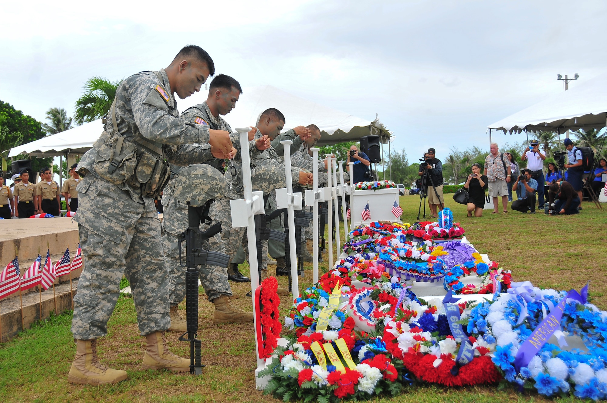 Soldiers from the Guam National Guard hang dog tags over their helmets during a grave-side tribute during the Memorial Day Ceremony at the Guam Governor’s Complex in Hagåtña, May 26, 2014. During the tribute, the Andersen Air Force Base Blue Knights honor guard paid respects to fallen service members by performing a 21-gun salute. (U.S. Air Force Photo by Staff Sgt. Brok McCarthy/Released)