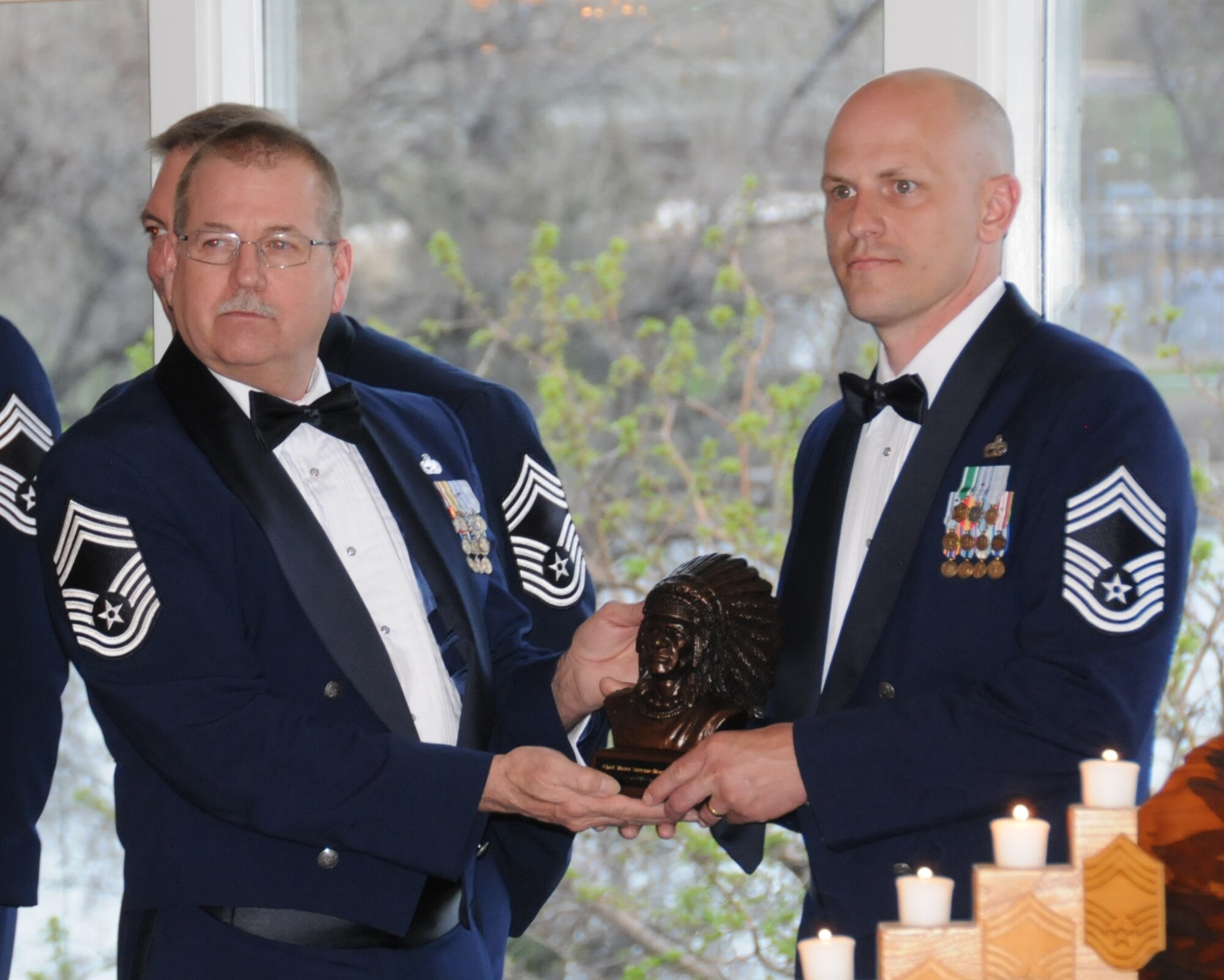 Chief Master Sgt. Steven Lynch, 120th Maintenance Group, presents a wooden bust of an Indian chief to a recently promoted Chief Master Sgt. Brian Furr, 219th RED HORSE, during the chief’s induction ceremony May 2 at the Meadow Lark Country Club in Great Falls, Montana.  (National Guard photo/Staff Sgt. Michael Touchette)