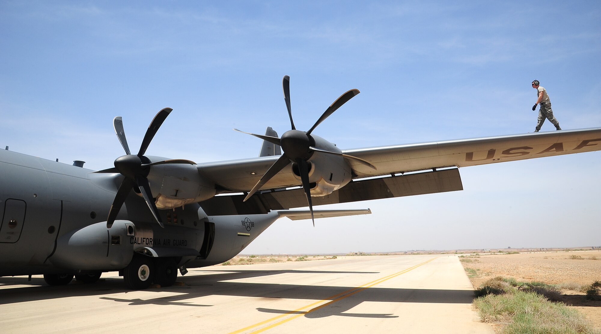 U.S. Air Force Senior Airman Beau Lewis, a crew chief with the 146th Aircraft Maintenance Squadron at Channel Islands Air National Guard Station, Calif., walks along the wing of a C-130J Hercules during Exercise Eager Lion May 29, 2014, at an air base in northern Jordan. During Eager Lion, the C-130s added another dimension to exercise scenarios, which included providing humanitarian assistance and disaster relief. (U.S. Air Force photo by Staff Sgt. Brigitte N. Brantley/Released)