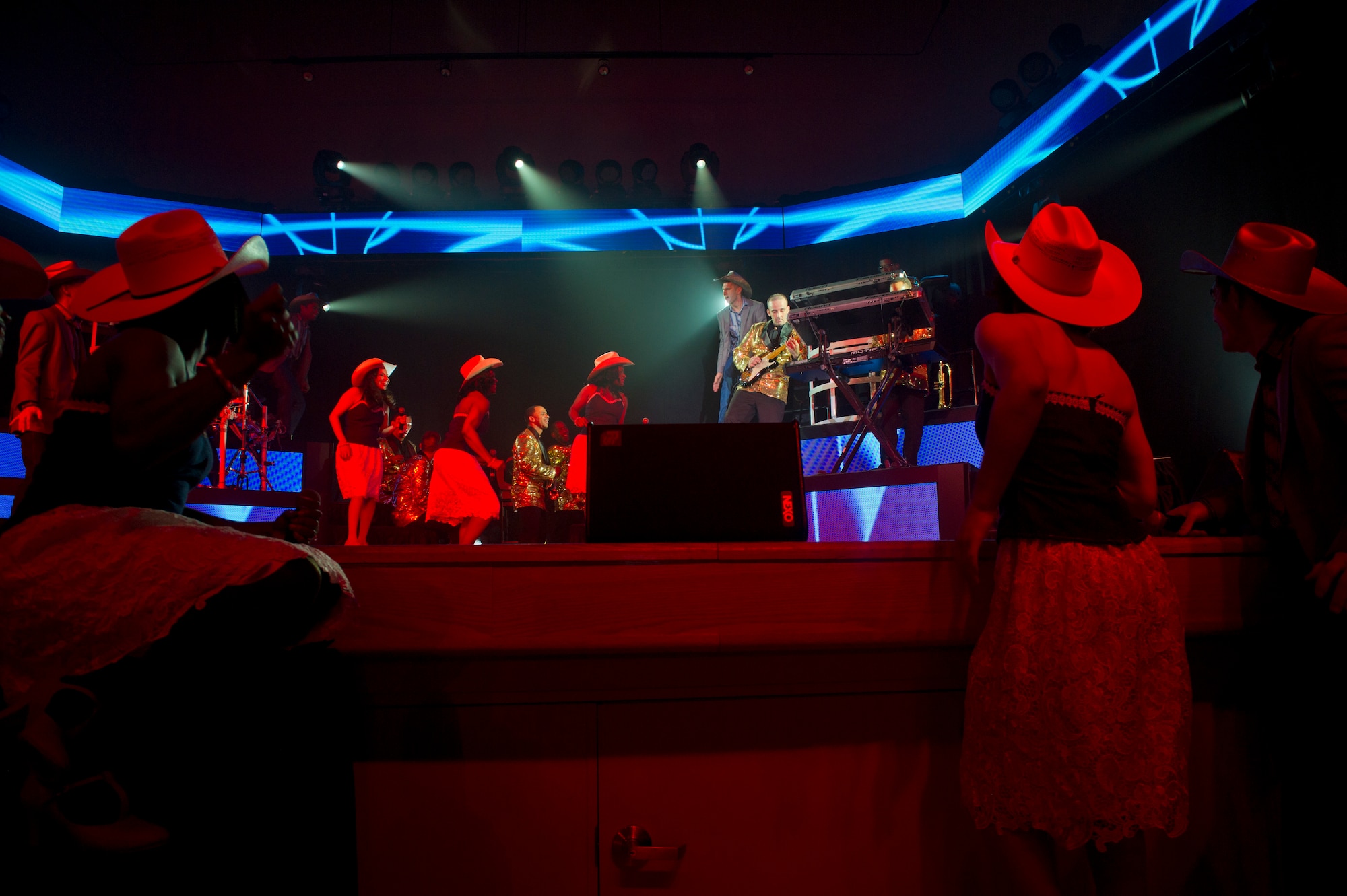 Members of Tops in Blue watch as Master Sgt. Justin Worley, 744th Communications Squadron cyber transport craftsman, plays a guitar solo during the Tops in Blue performance at Tays Center, Alamogordo, N.M., May 31. Tops in Blue is comprised of vocalists, musicians, dancers and technicians serving in the U.S. Air Force. The group’s primary mission is to perform for military personnel and their families throughout the world. (U.S. Air Force photo by Airman 1st Class Aaron Montoya / Released)