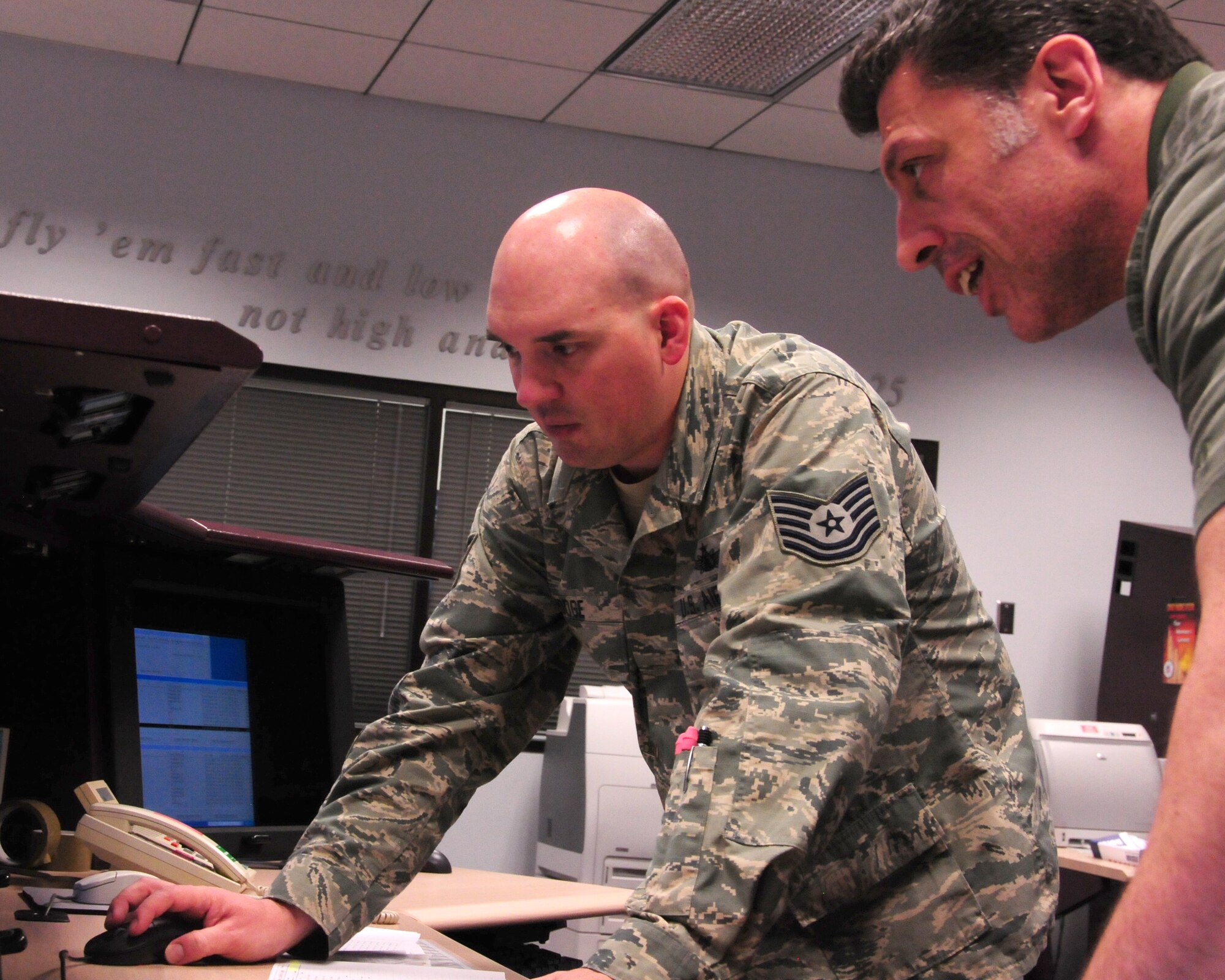 Air Force Reserve Tech. Sgt. David Hodge, 6th Space Operations Squadron Non-Commissioned Officer in Charge of standardization and evaluation, and Paul Apostolopoulos, National Oceanic and Atmospheric Administration engineer, discuss satellite orbit and planning tools during an annual Continuity of Operations Plan at Schriever AFB, Colo.  The COOP exercise provides military and civilian operators a chance to exchange new ideas, techniques and procedures, and enhance operations at facilities in Suitland, Md., and Schriever AFB. (U.S. Air Force photo/Tech. Sgt. Jeff Ftizmorris)