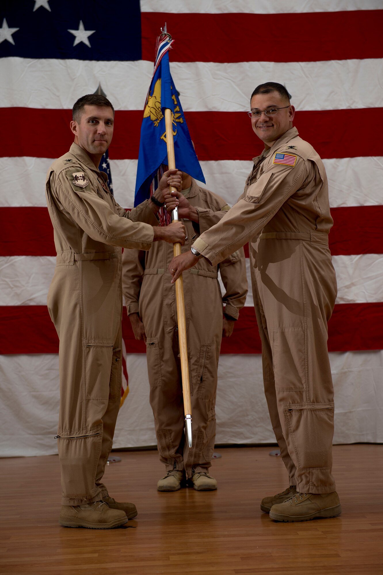 U.S. Air Force Col. John Klein, 386th Air Expeditionary Wing commander, hands the 386th Expeditionary Operations Group guidon to Col. Douglas DeLaMater during a change of command ceremony June 1, 2014 at an undisclosed location in Southwest Asia. Santos comes from the U.S. Transportation Command, Scott Air Force Base, Illinois where he was the deputy chief, west division and deployment and distribution operations center chief. (U.S. Air Force photo by Staff Sgt. Jeremy Bowcock)