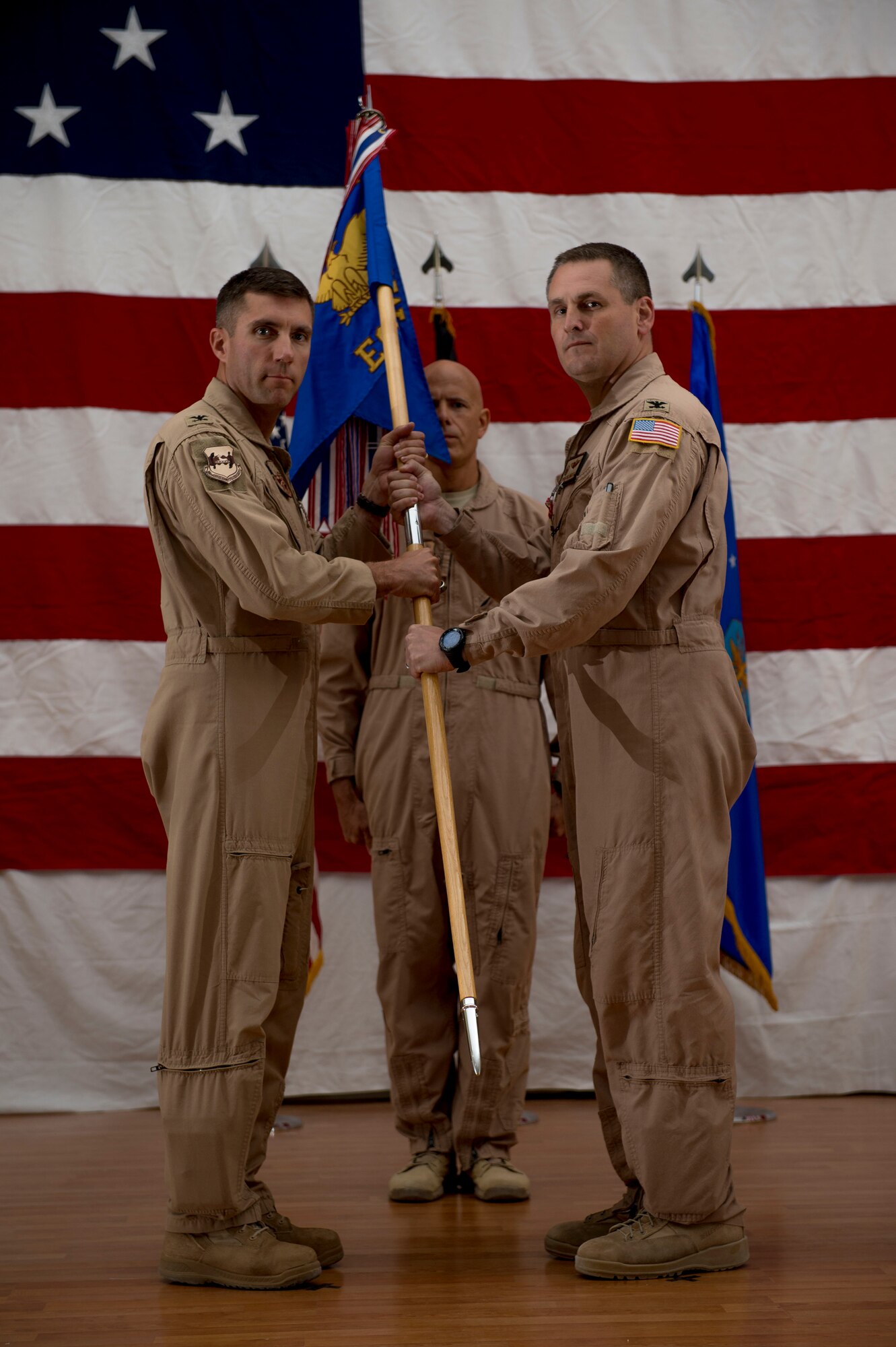 U.S. Air Force Col. Douglas DeLaMater hands the 386th Expeditionary Operations Group guidon to Col. John Klein, 386th Air Expeditionary Wing commander, during a change of command ceremony June 1, 2014 at an undisclosed location in Southwest Asia. DeLaMater relinquished command of the 386th EOG to Col. Joe Santos and will be assuming command of 374th Airlift Wing, Yokota Air Base, Japan. (U.S. Air Force photo by Staff Sgt. Jeremy Bowcock)