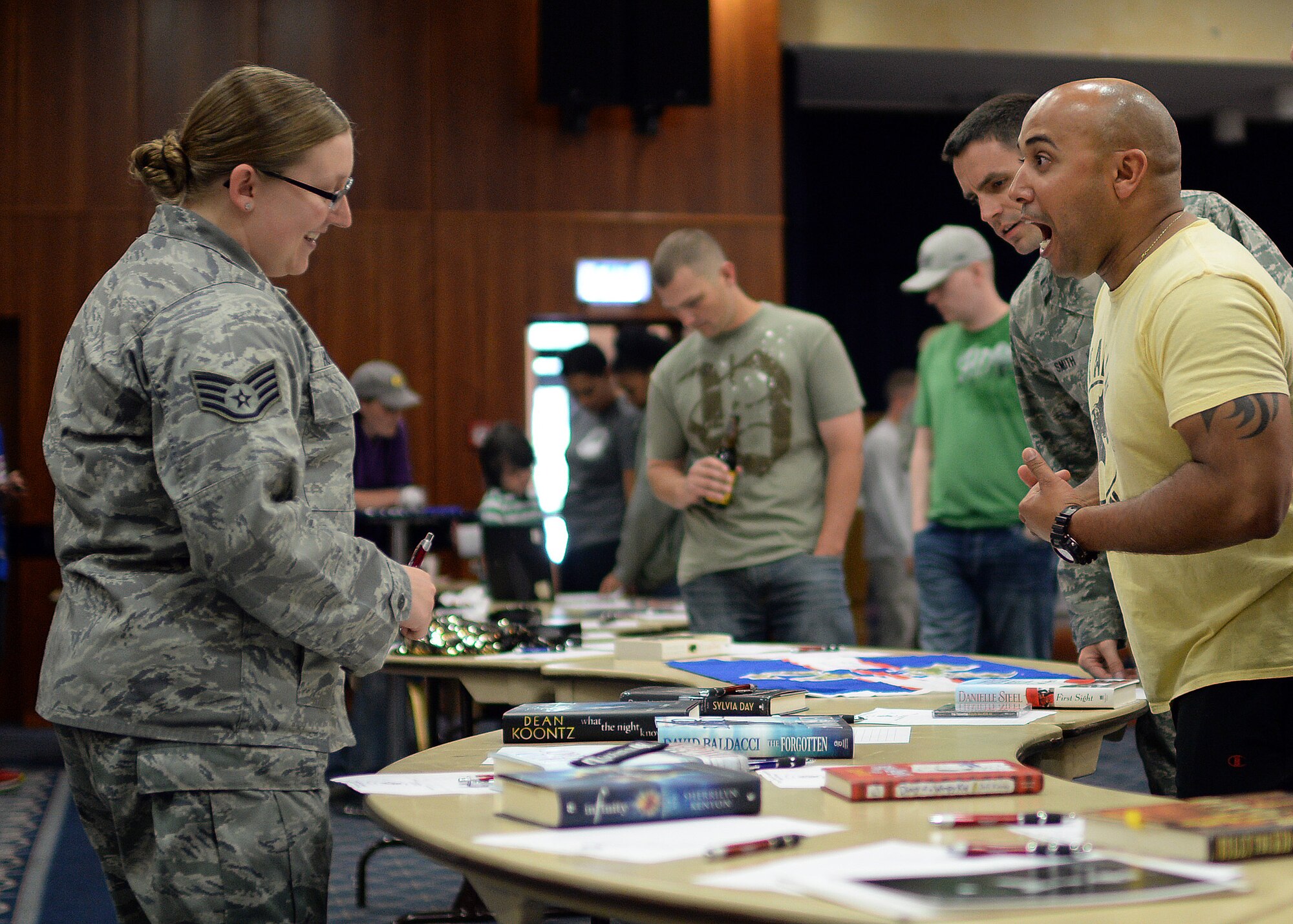 U.S. Air Force Staff Sgt. Sara Howard, 52nd Comptroller Squadron and Rathdrum, Idaho, native bargains with U.S. Air Force Master Sgt. Jason Garo, 52nd Operations Support Squadron first sergeant, over an autographed novel by horror and suspense writer Dean Koontz during a silent auction in Club Eifel at Spangdahlem Air Base, Germany, May 30, 2014. Nearly 250 items were up for bid at the event, and the all the proceeds went to the Fisher House Foundation and Operation Warmheart. (U.S. Air Force photo by Staff Sgt. Daryl Knee/Released)