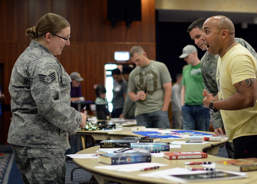 U.S. Air Force Staff Sgt. Sara Howard, 52nd Comptroller Squadron and Rathdrum, Idaho, native bargains with U.S. Air Force Master Sgt. Jason Garo, 52nd Operations Support Squadron first sergeant, over an autographed novel by horror and suspense writer Dean Koontz during a silent auction in Club Eifel at Spangdahlem Air Base, Germany, May 30, 2014. Nearly 250 items were up for bid at the event, and all of the proceeds went to the Fisher House Foundation and Operation Warmheart. (U.S. Air Force photo by Staff Sgt. Daryl Knee/Released) 
