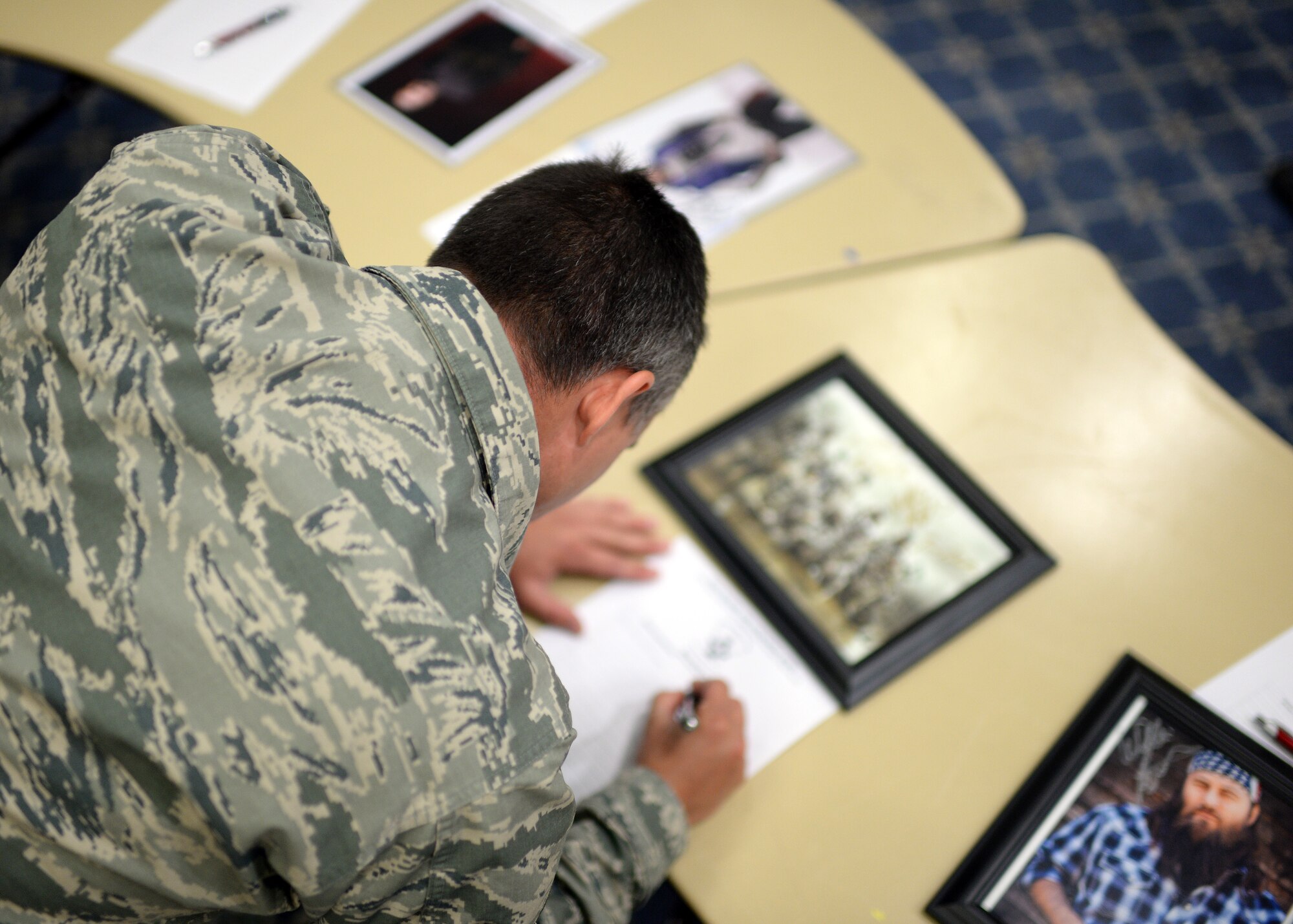 U.S. Air Force Staff Sgt. Casey Cason, 338th Training Squadron and Baker's Field, Calif., native, bids on an autographed photograph from the members of the T.V. show "Duck Dynasty" during a silent auction in Club Eifel at Spangdahlem Air Base, Germany, May 30, 2014. The base's First Sergeant Council organized this silent auction of nearly 250 memorabilia items to raise money for the Fisher House Foundation, an organization that provides military families a housing option near their service member who was hospitalized for an illness, disease or injury. (U.S. Air Force photo by Staff Sgt. Daryl Knee/Released)