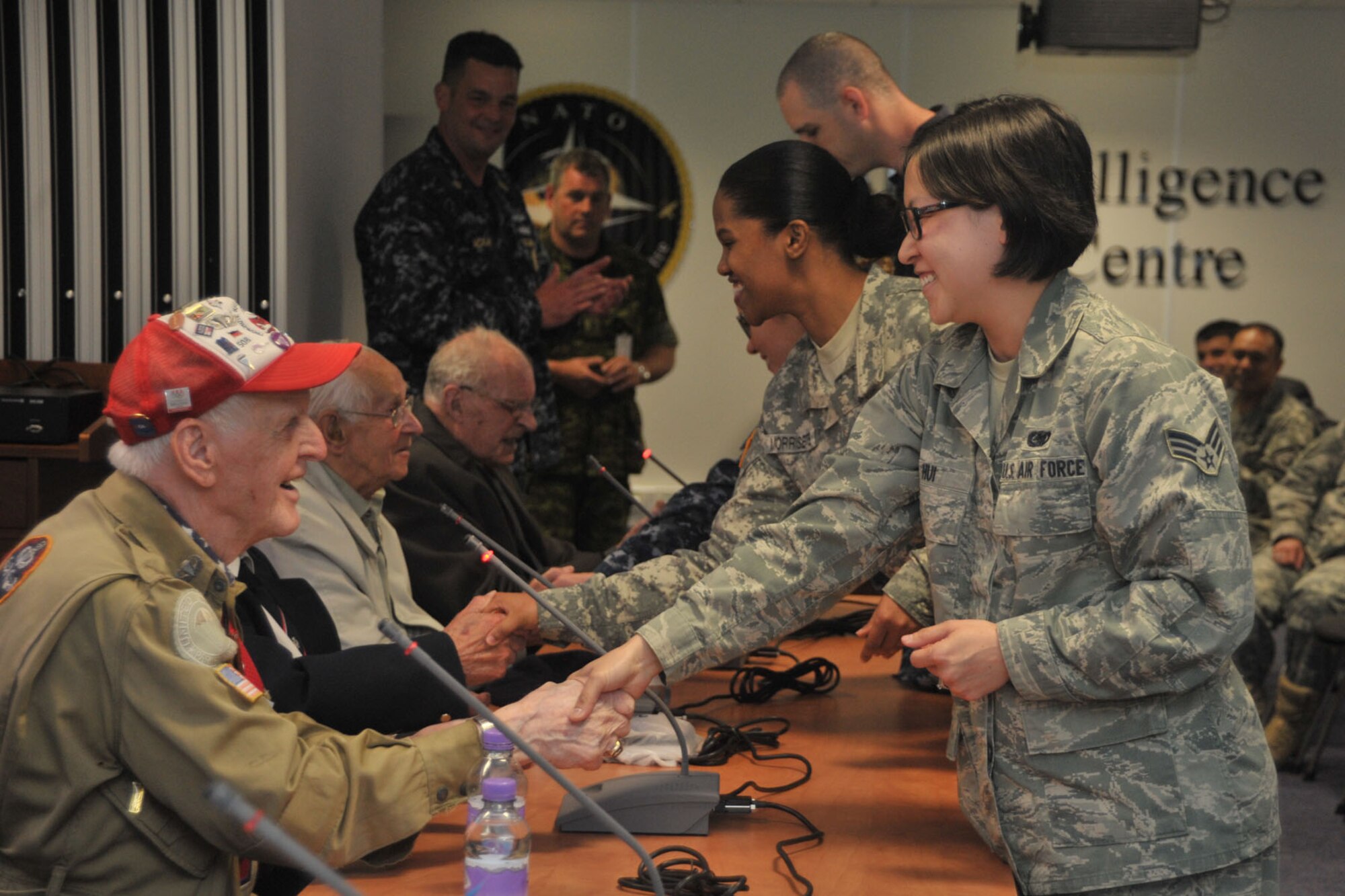 Service members assigned to the Joint Intelligence Operations Center, Europe Analytic Center, present coins to World War II veterans during a WWII panel at RAF Molesworth, United Kingdom May 27, 2014. Personnel assigned to RAF Molesworth and Alconbury attended the event to ask questions about what happened during the invasion of Normandy, France and show their appreciation by presenting gifts to the veterans. (U.S. Air Force photo by Staff Sgt. Ashley Hawkins/Released)