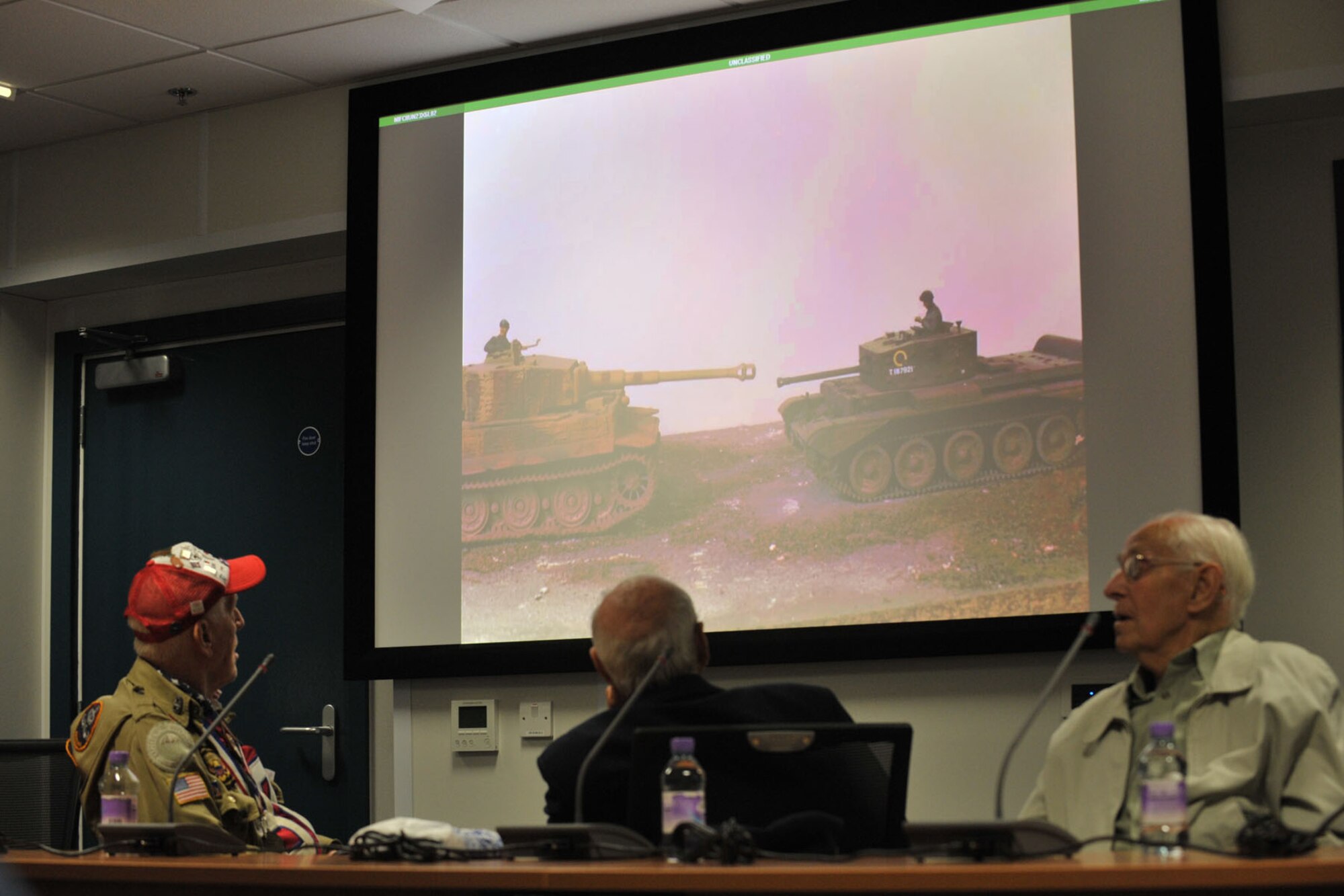 Retired U.S. Army Sgt. Ernie Lamson, Royal Navy Petty Officer Harry Eddy and “Bevin Boy” Dennis Hill watch a slideshow presentation about the Allied Forces’ combat missions and the weapons used during a World War II panel at RAF Molesworth, United Kingdom May 27, 2014. Personnel assigned to RAF Molesworth and Alconbury received historical information about Allied and Axis forces’ machinery, first-hand information of the veterans’ experiences and a look into life after the war. (U.S. Air Force photo by Staff Sgt. Ashley Hawkins/Released)
