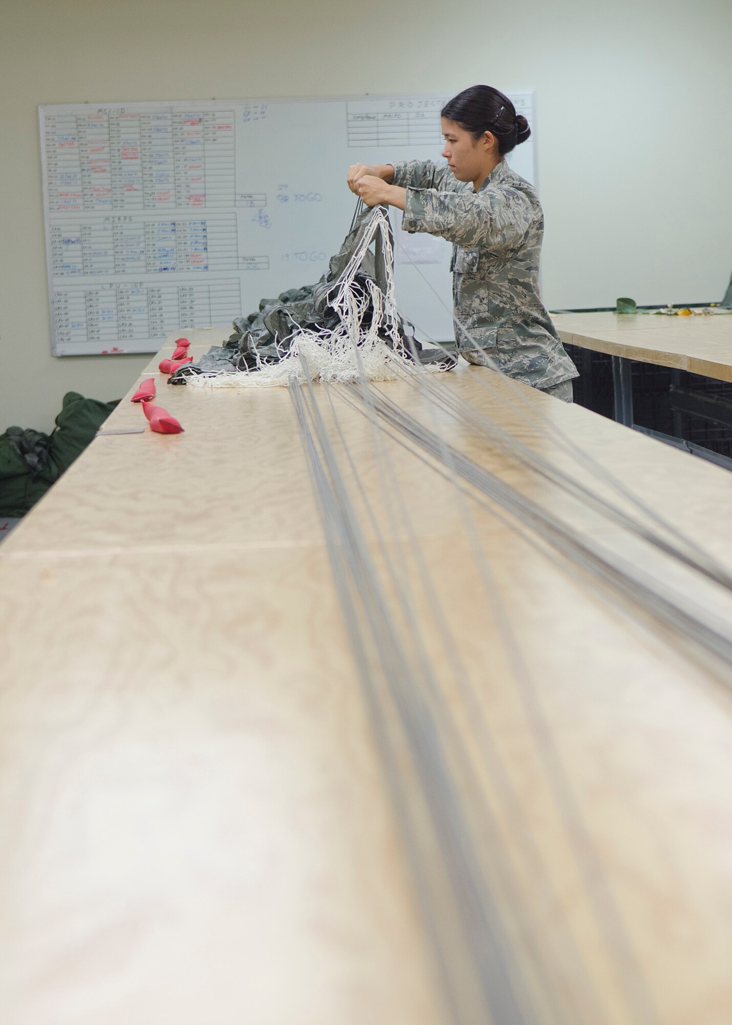 Staff Sgt. Jamie Williams, 36th Operations Support Squadron aircrew flight equipment craftsman, examines a parachute during a quality assurance inspection May 20, 2014, at Andersen Air Force Base, Guam. Aircrew flight equipment Airmen inspect, maintain, pack and adjust equipment such as flight helmets, oxygen masks, parachutes, flotation devices, and survival kits.(U.S. Air Force photo by Senior Airman Katrina M. Brisbin/Released)