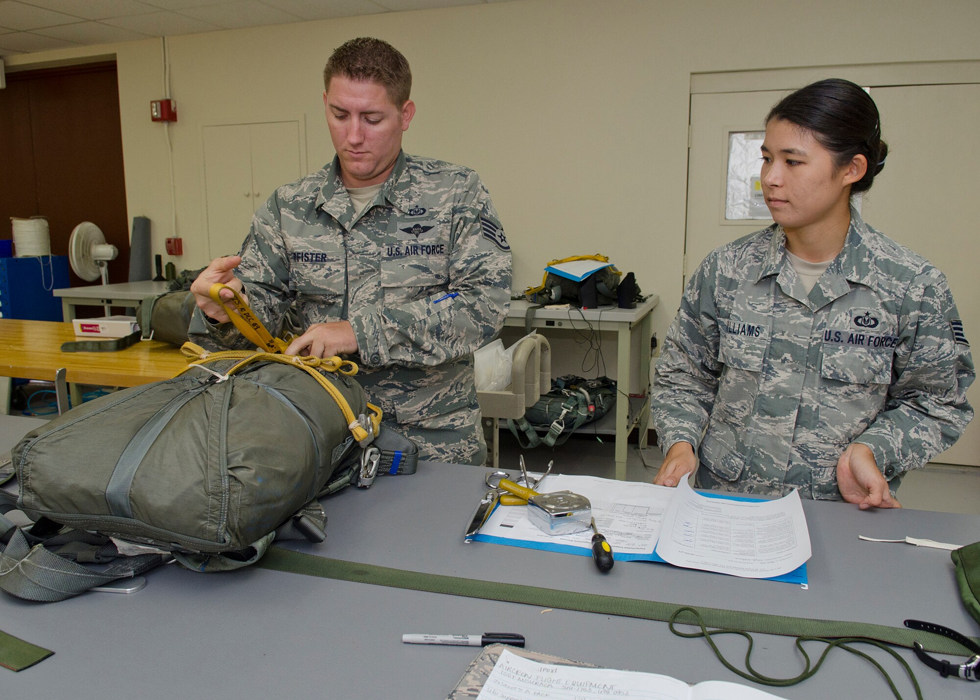 Staff Sgt. Matthew Pfister, 36th Operations Support Squadron aircrew flight equipment craftsman, inspects a parachute packed by Staff Sgt. Jamie Williams, 36 OSS AFE craftsman, May 20, 2014, at Andersen Air Force Base, Guam. Each piece of equipment is inspected and then checked again to ensure it meets all safety regulations.  (U.S. Air Force photo by Senior Airman Katrina M. Brisbin/Released)