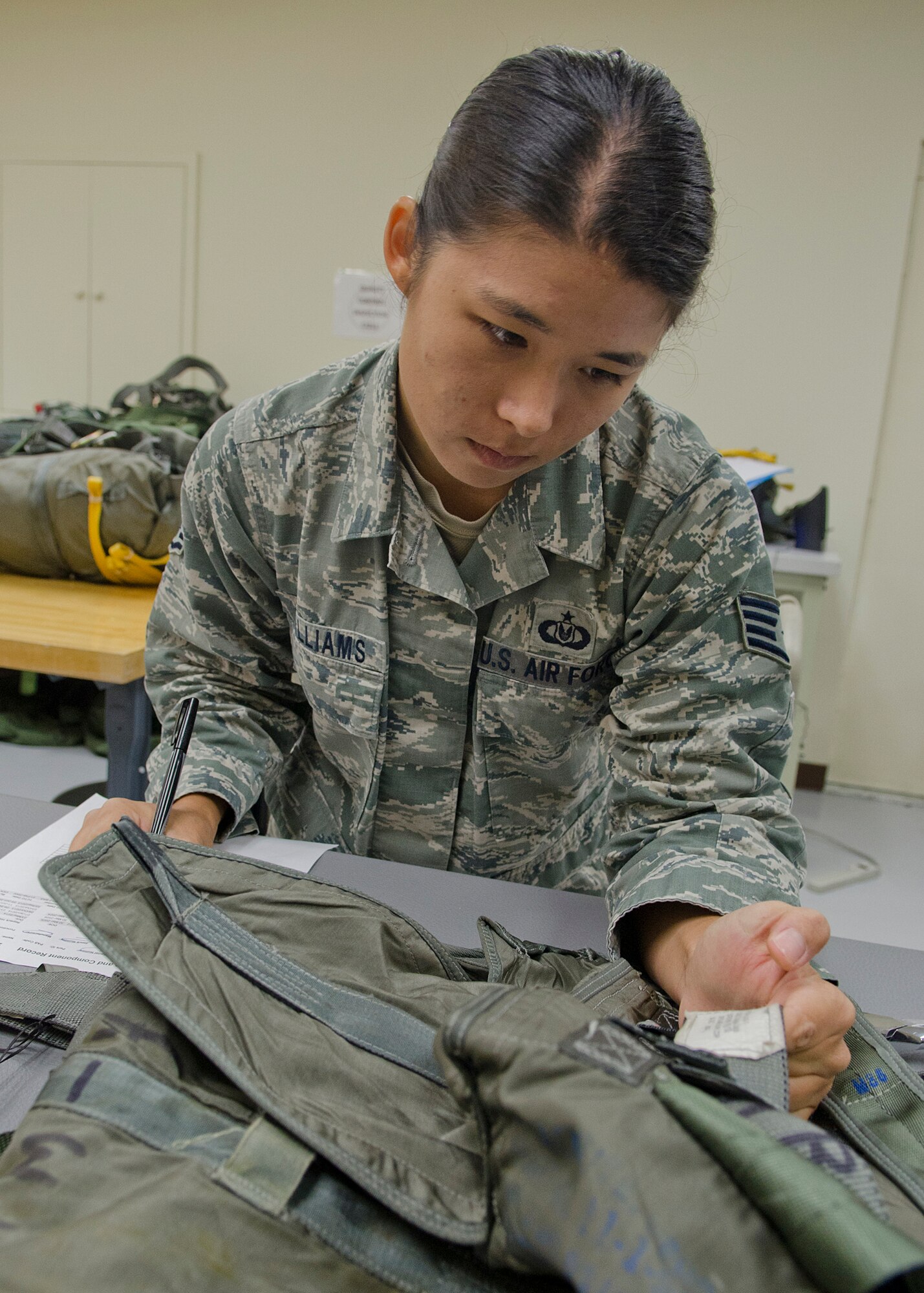 Staff Sgt. Jamie Williams, 36th Operations Support Squadron aircrew flight equipment craftsman, verifies identification numbers on a parachute pack May 20, 2014, at Andersen Air Force Base, Guam. Aircrew flight equipment Airmen manage, perform and schedule inspections, maintenance and adjustments on assigned aircrew flight equipment, defense equipment and associated supplies. (U.S. Air Force photo by Senior Airman Katrina M. Brisbin/Released)