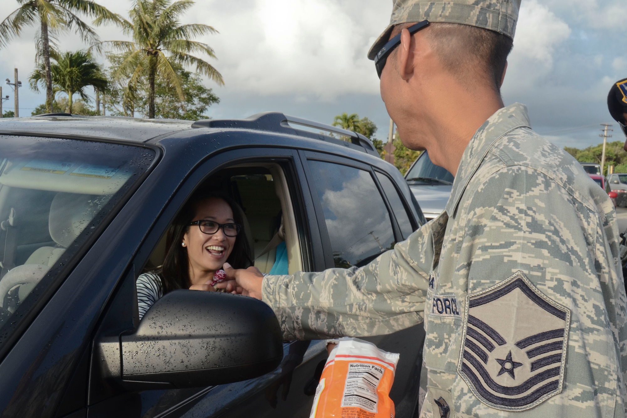 Master Sgt. Bradley Dapilmoto, 36th Wing Staff Agency first sergeant, hands a piece of candy to a driver entering Andersen Air Force Base, Guam at the main gate May 22, 2014. Base senior leadership handed out candy advertising the Critical Days of Summer 2014 Theme "Risk:  Double Checks, Not Second Thoughts".  (U.S. Air Force photo by Airman 1st Class Emily A. Bradley/Released)