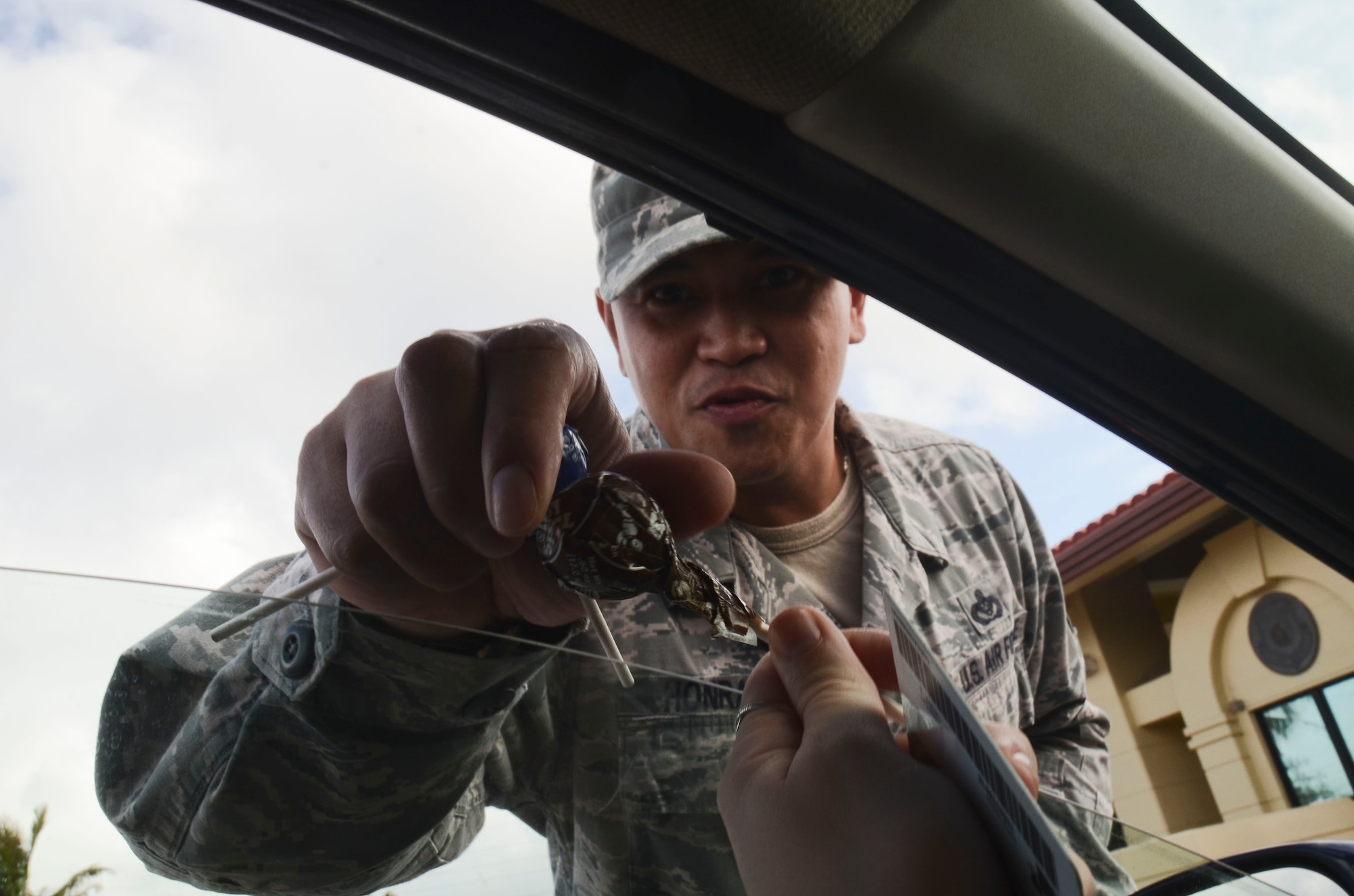 Master Sgt. Michael Honrado, 36th Civil Engineer Squadron, hands candy to a driver entering Andersen Air Force Base, Guam through the main gate May 22, 2014. Base senior leadership handed out candy advertising the Critical Days of Summer 2014 Theme "Risk:  Double Checks, Not Second Thoughts". (U.S. Air Force photo by Airman 1st Class Emily A. Bradley/Released)