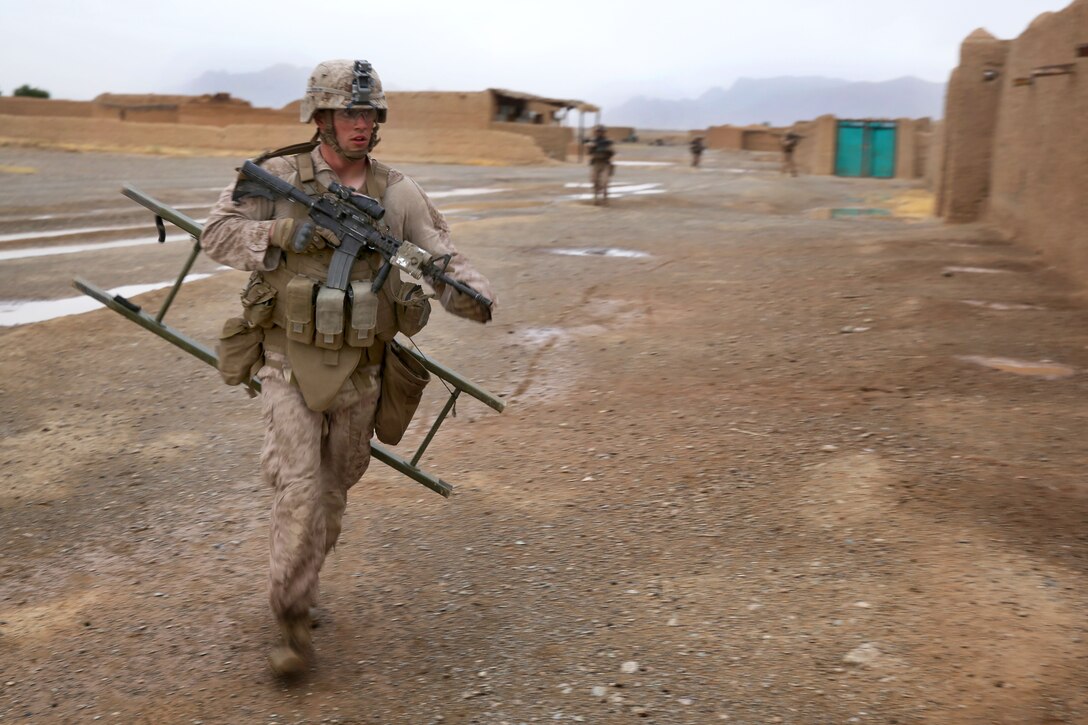 U.S. Marine Corps Lance Cpl. Benjamin Knipp runs to aid U.S. Marines with a combat ladder during a mission in Larr village in Helmand province, Afghanistan, May 15, 2014. Knipp, a rifleman, is assigned to Bravo Company, 1st Battalion, 7th Marine Regiment.