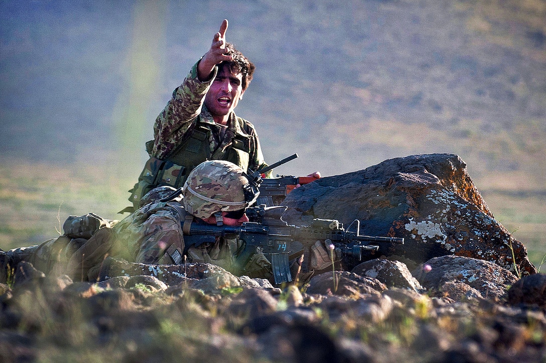An Afghan soldier directs fellow soldiers during a firefight near Combat Outpost Giro while a U.S. Army paratrooper fires on insurgent positions in Afghanistan's Ghazni province, May 17, 2012.  
