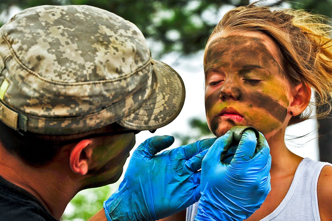 A soldier transforms 7-year-old Kayiah into a camouflaged Army Ranger at the 6th Ranger Training Battalion’s annual open house on Eglin Air Force Base, Fla., May 12, 2012. The event enabled the public to learn how Rangers train and operate, showing dive equipment, weapons, a reptile zoo and zodiac boats.  
