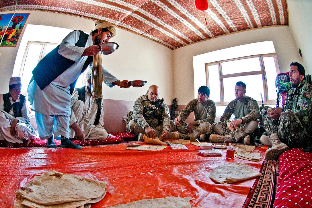 An Afghan villager offers food to U.S. Army Capt. Robert Gacke and several of his troops during a meeting with village elders in Afghanistan's southern Ghazni province, May 4, 2012. Gacke, a company commander, is assigned to the 82nd Airborne Division’s Company C, 2nd Battalion, 504th Parachute Infantry Regiment, 1st Brigade Combat Team.  
