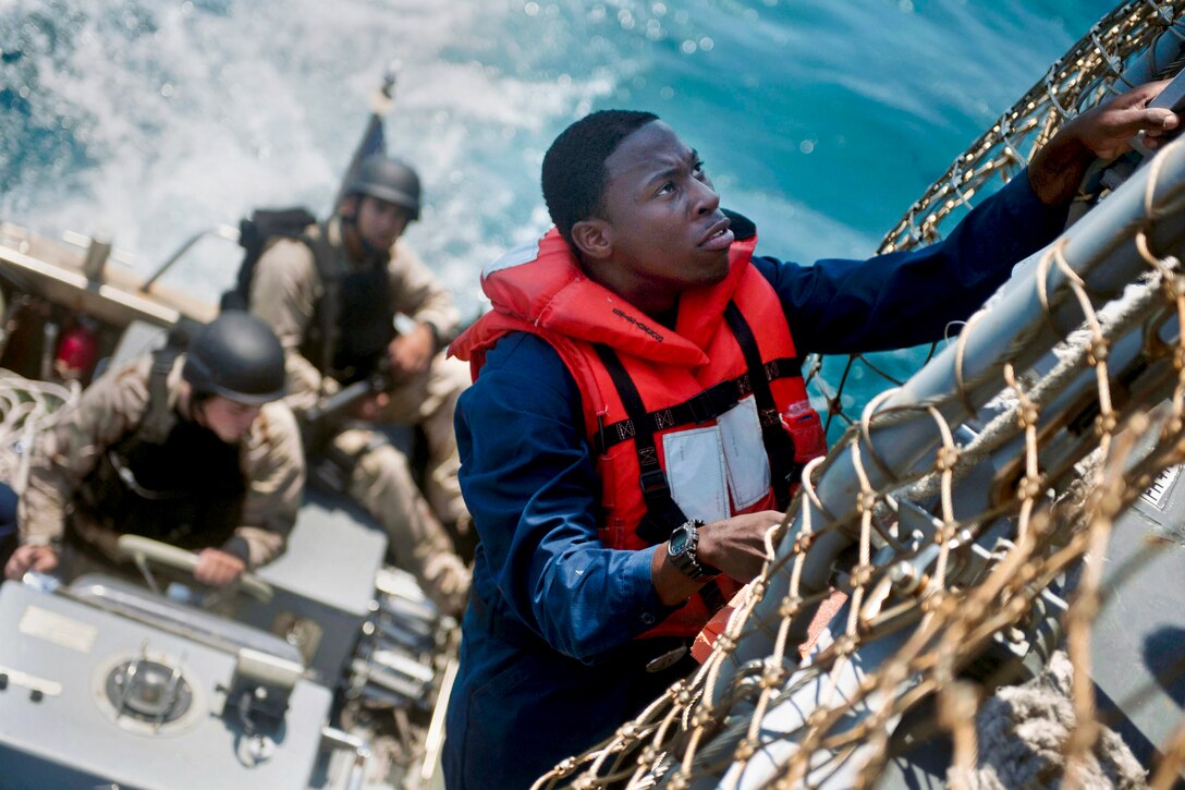 U.S. Navy Seaman Julius McGowan climbs down to a rigid-hull inflatable boat during a boarding exercise in the Atlantic Ocean, May 6 2012. McGowan is assigned to the ship-control team aboard the guided-missile destroyer USS Jason Dunham, which is conducting a training exercise in the Atlantic Ocean.  
