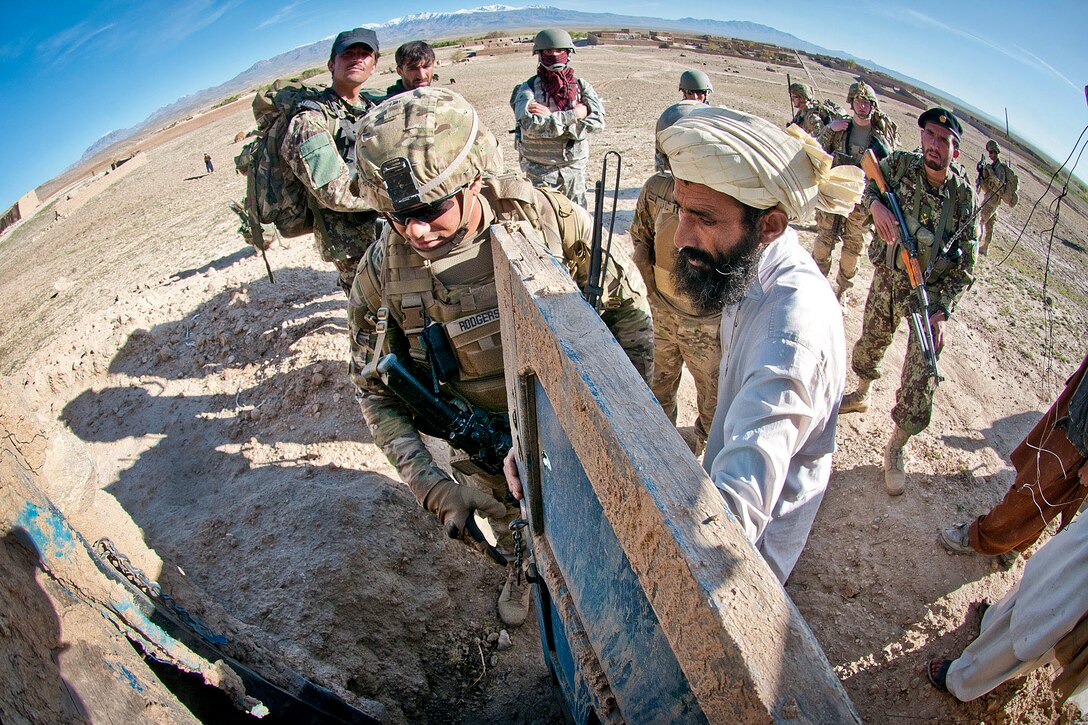 An Afghan villager unlocks the door of a suspected homemade explosives factory for U.S. Army Spc. Timothy Rodgers in Afghanistan's Ghazni province, May 4, 2012. Rodgers is assigned to the 82nd Airborne Division’s 1st Brigade Combat Team.  
