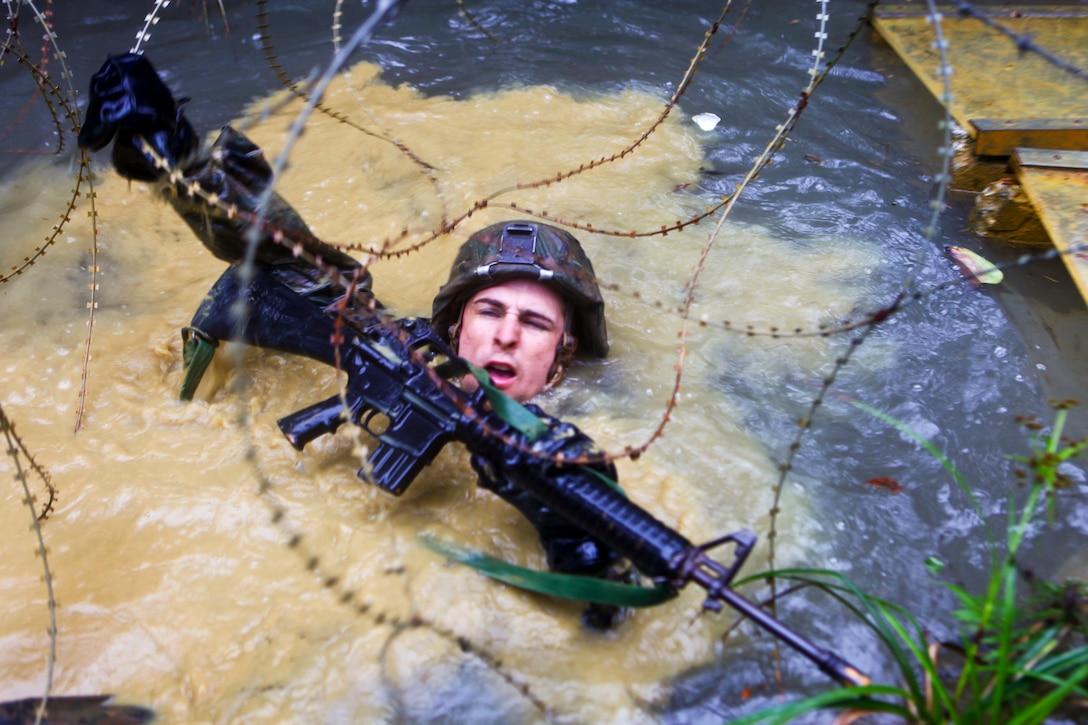 A U.S. Marine crawls through a watery ditch and under concertina wire during a jungle endurance course on Camp Gonsalves, Okinawa, April 20, 2012. After completing a two-week training evolution at the Jungle Warfare Training Center, the Marines took the four-mile-long course through the Okinawan jungle, using rappelling, rope-crossing and other skills they learned.  
