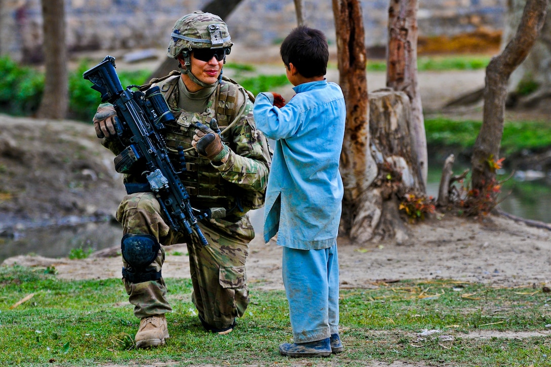 U.S. Army Pfc. Jared Baughn learns Pashtu from an Afghan child while on patrol on Combat Outpost Terezayi in Afghanistan's Khowst province, April 10, 2012. Baughn is assigned to Company C, 1st Battalion, 501st Infantry Regiment.  
