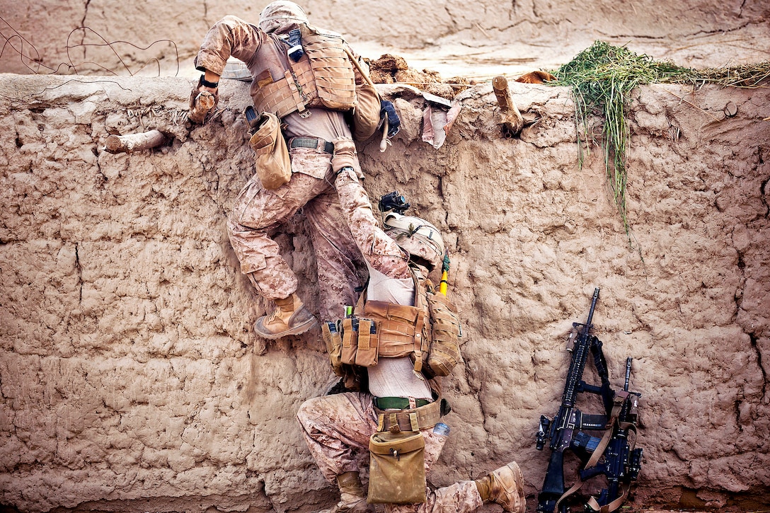 U.S. Marine Cpl. Enrique Torres, right, helps U.S. Marine Corps Lance Cpl. Joseph Hevia, top, climb onto a roof while searching a compound with Afghan policemen during Operation Zema Parma Sar Tera in the Garmsir district in Afghanistan's Helmand province, April 14, 2012. Torres, a squad leader, and Hevia, a rifleman, are assigned to Kilo Company, 3rd Battalion, 3rd Marine Regiment. 
