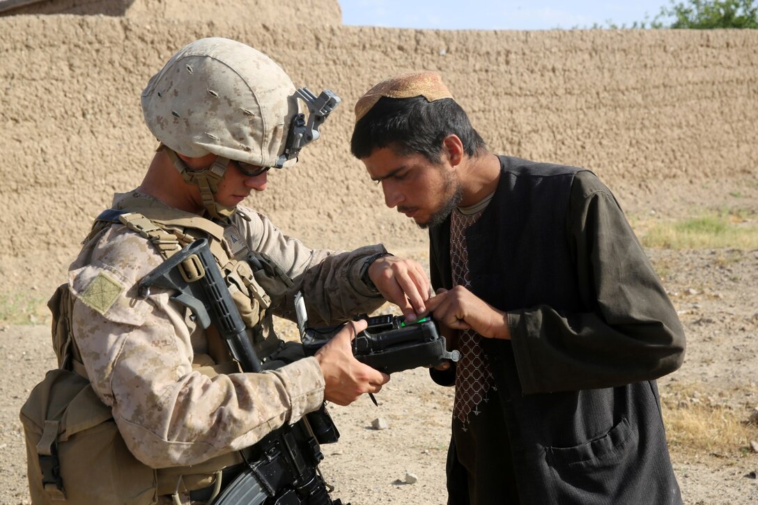 Lance Cpl. Kesley Farmer, rifleman, Bravo Company, 1st Battalion, 7th Marine Regiment, and a native of Stacy, Minnesota, utilizes a Biometric Enrollment and Screening Device during a mission in Helmand province, Afghanistan, May 15, 2014. The company operated in Larr Village for two days to establish a presence and to disrupt enemy fighters. Throughout the mission the infantrymen conducted several patrols within the village and discovered hazardous materials which could be used to create improvised explosive devices.