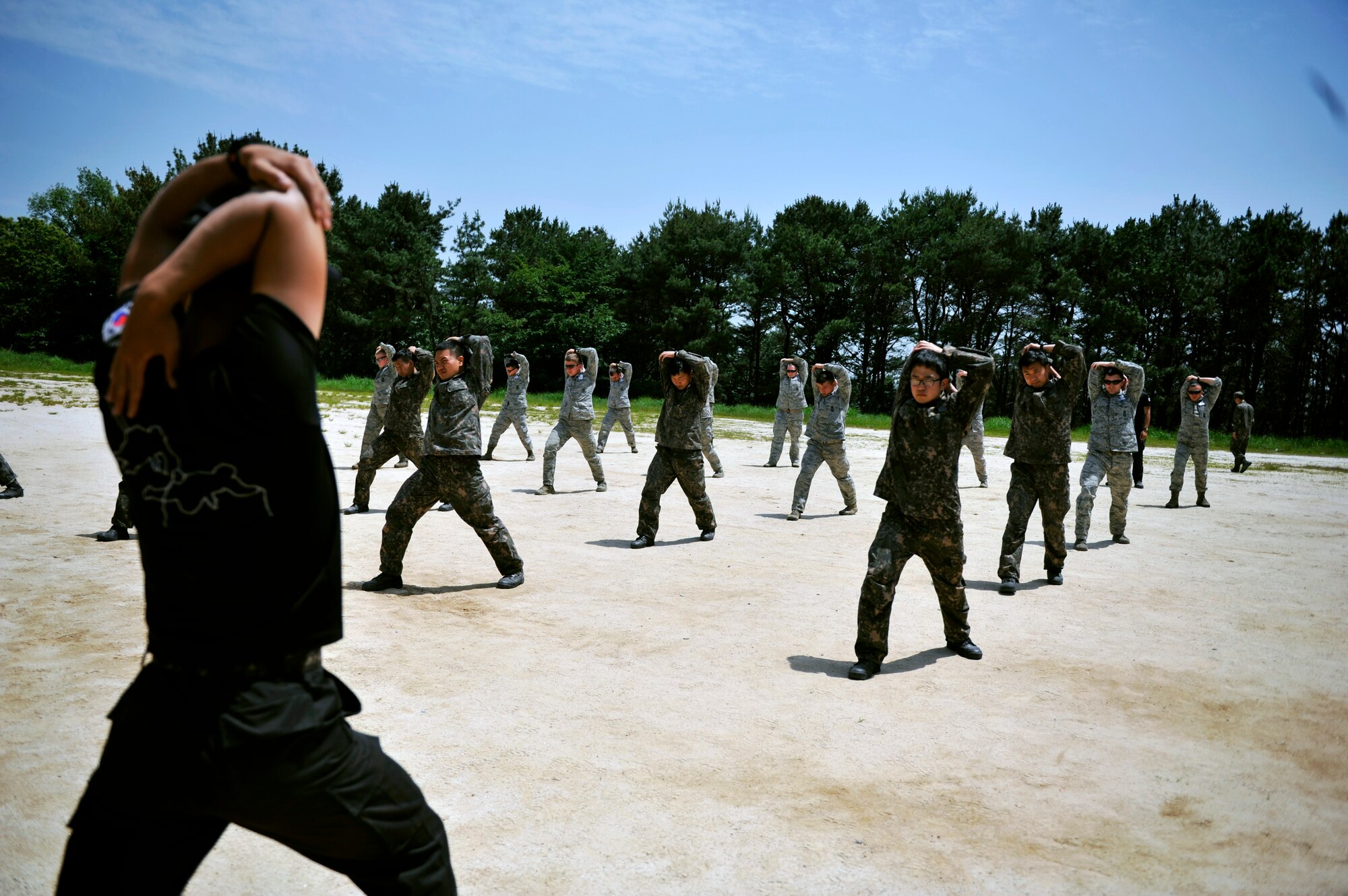 An instructor leads Republic of Korea air force airmen and U.S. Air Force security forces Airmen in a stretch prior to completing training during the ROK Ranger Qualification Course on Jinju Air Base, ROK, May 27, 2014. The course is where ROK airmen will go before joining the special duty team that secures airports and other sensitive areas on the Korean peninsula. (U.S. Air Force photo/Senior Airman David Owsianka)