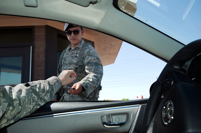 Airman 1st Class Gregory Vasquez, 99th Security Forces Squadron journeyman, checks a common access card June 3, 2014 at the entrance of Nellis Air Force Base, Nev. Employee-Certification and Reporting System program which was scheduled to begin June 1, has been postponed until further notice due to program technical problems. For more information about ECARS, please email questions to NellisAirQuality@nellis.af.mil. (U.S. Air Force photo by Senior Airman Timothy Young)
