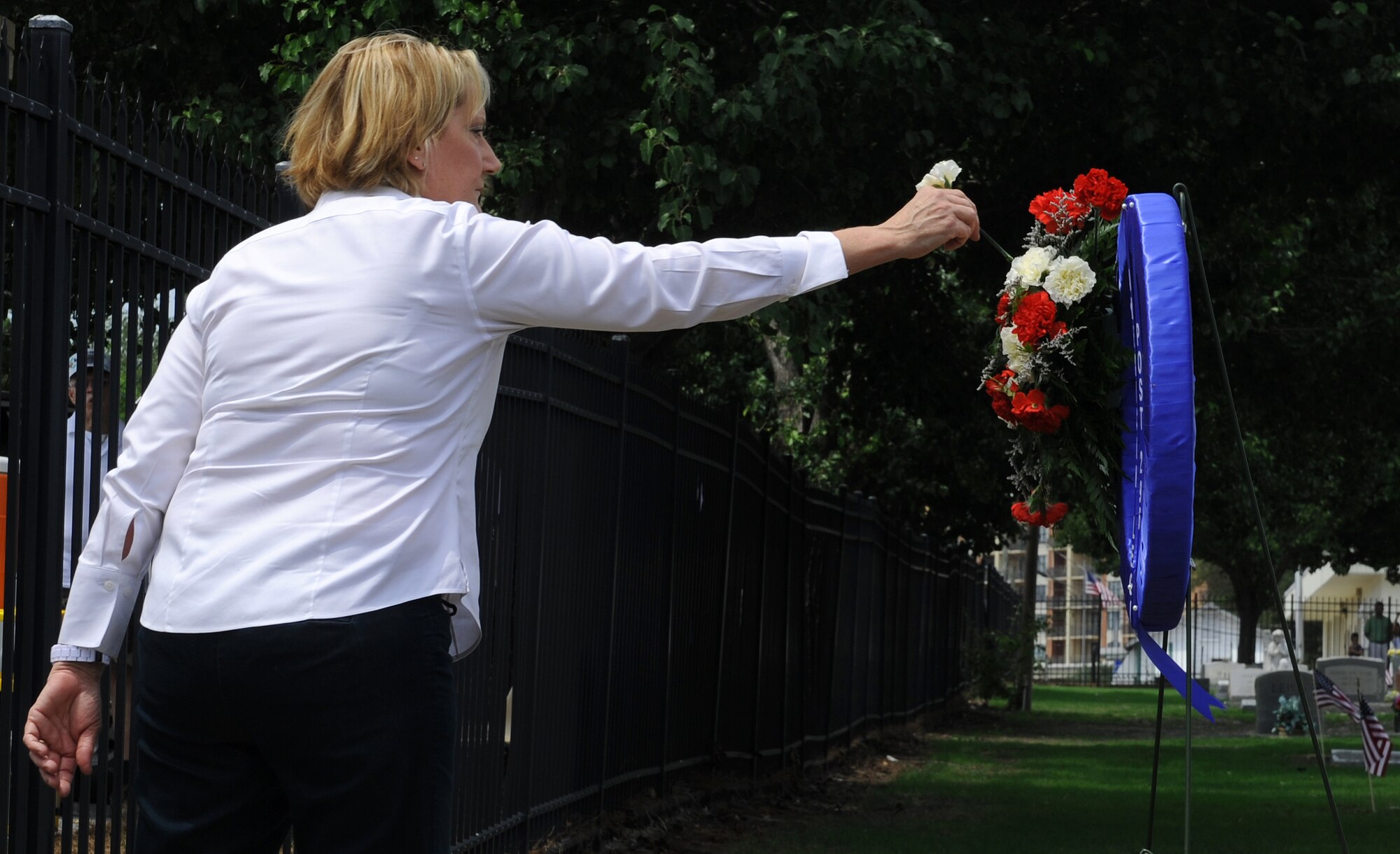 Terri Griffin, American Legion Sergeant-at-Arms, places a flower on a wreath during the American Legion Memorial Day Ceremony at the Destin Memorial Cemetery, Destin, Fla., May 26, 2014. Memorial Day is a national holiday held to honor those who have died in service to their country. (U.S. Air Force photo/Senior Airman Kentavist P. Brackin)